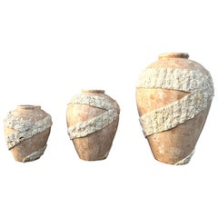 Ensemble de trois grands vases de sol postmodernes en pierre de Mactan, ornés de pompons. Vers 1980.