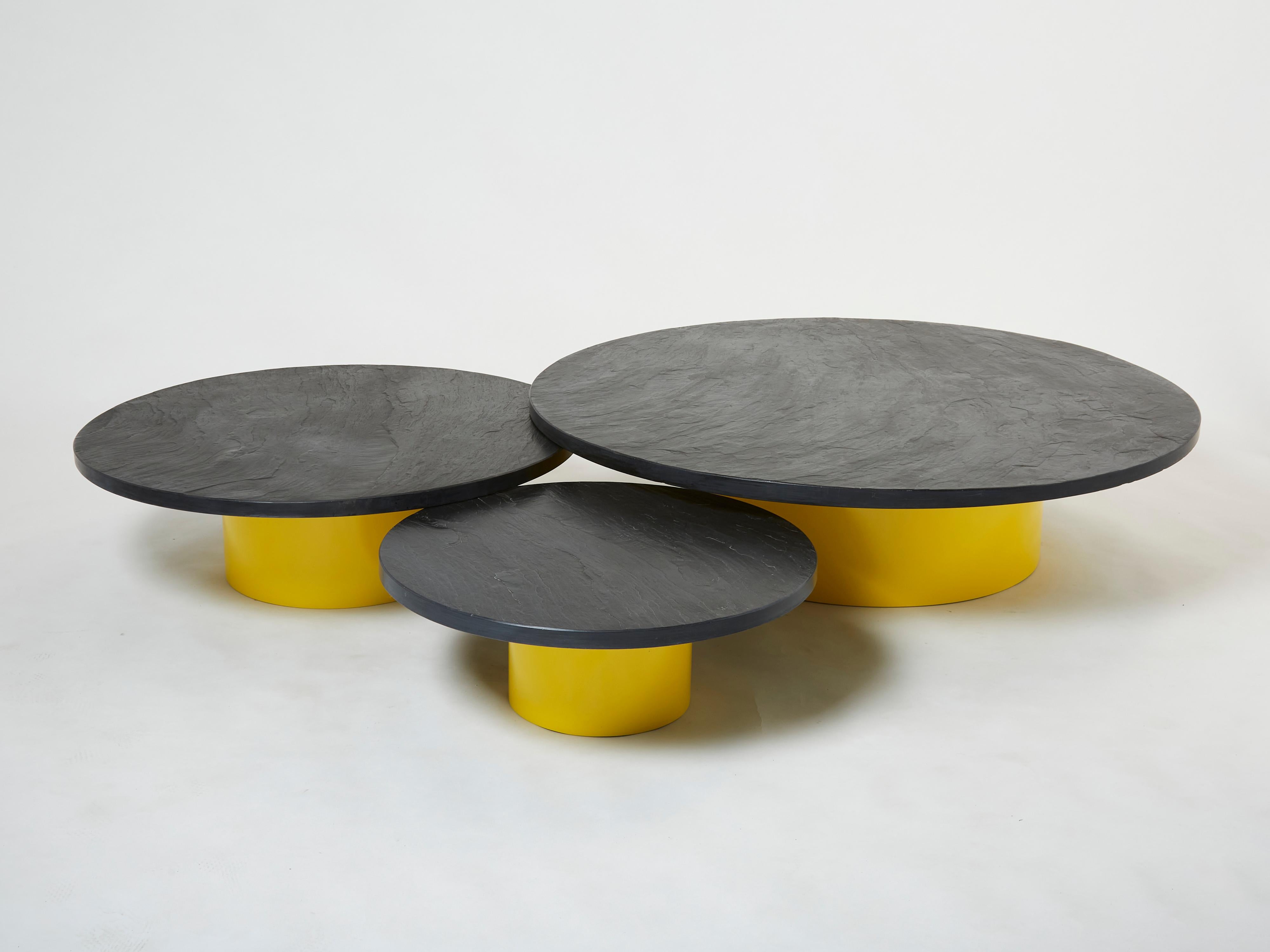 This is a unique set of three large round nesting tables forming a big 80+ inches wide coffee table made in France in the late 1970s from a beautiful French slate, with yellow lacquer wood bases. The thick surface of each table feels strong and