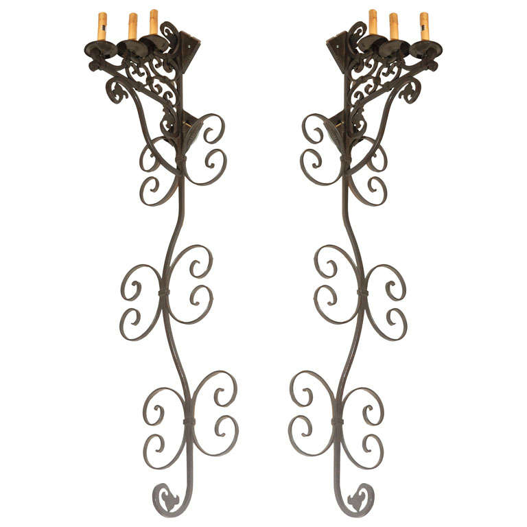 Set of three very large Moorish Spanish style wrought iron wall sconces with three candle lights.
Iron is black finish.
Wired for electricity ready to install.


    