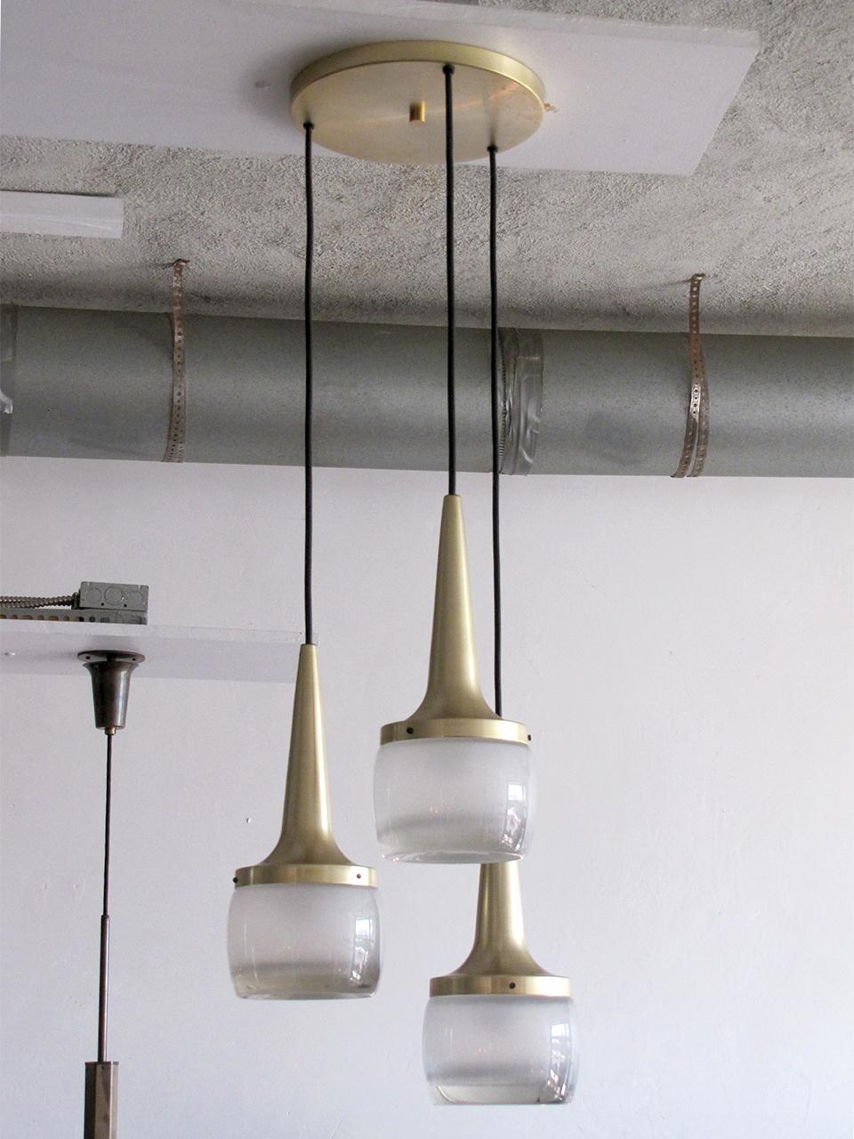 set of three pendant lights by Staff, brushed brass and heavy molded glass, wired for US standards, dimmable, three E27 sockets, max. wattage 60w per pendant or LED equivalent, bulbs provided as a onetime courtesy, Can be hung individually.