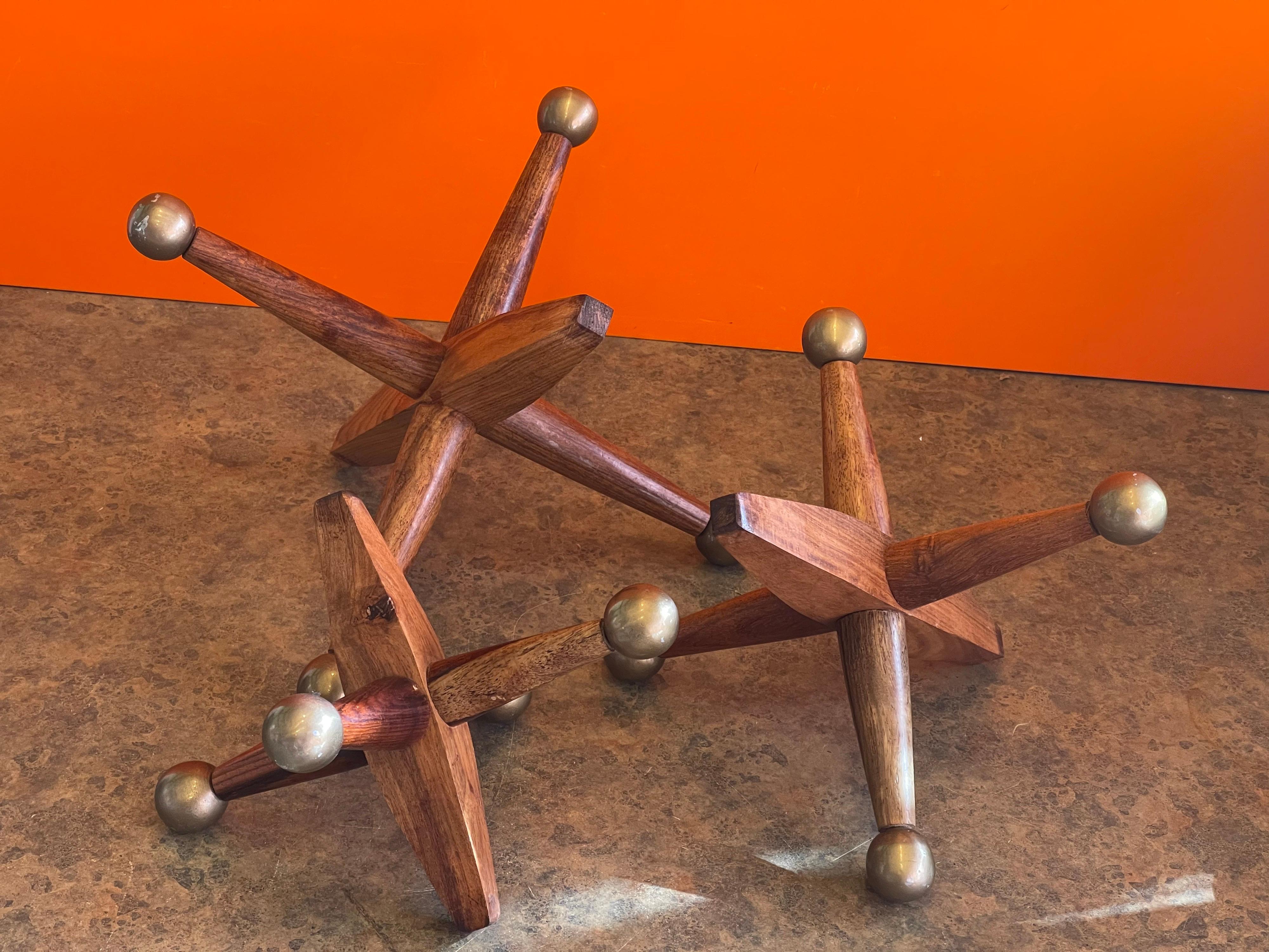Nice set of three large wood & brass capped atomic jacks / jax in the style of Bill Curry, circa 1980s. The pieces can be used as bookends, a doorstop or decorative accent. The jacks dimensions are as follows: 

Measures: Sm: 8 W x 8 D x 6 H
Med: