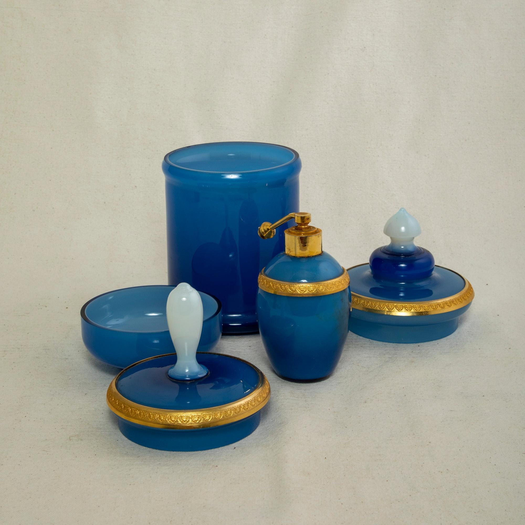 This set of three late nineteenth century French blue opaline vanity bottles features gilt bronze rims detailed with a palmette motif. Found in Chartres, France, this stunning trio includes two jars with lids for powder and cotton balls and a