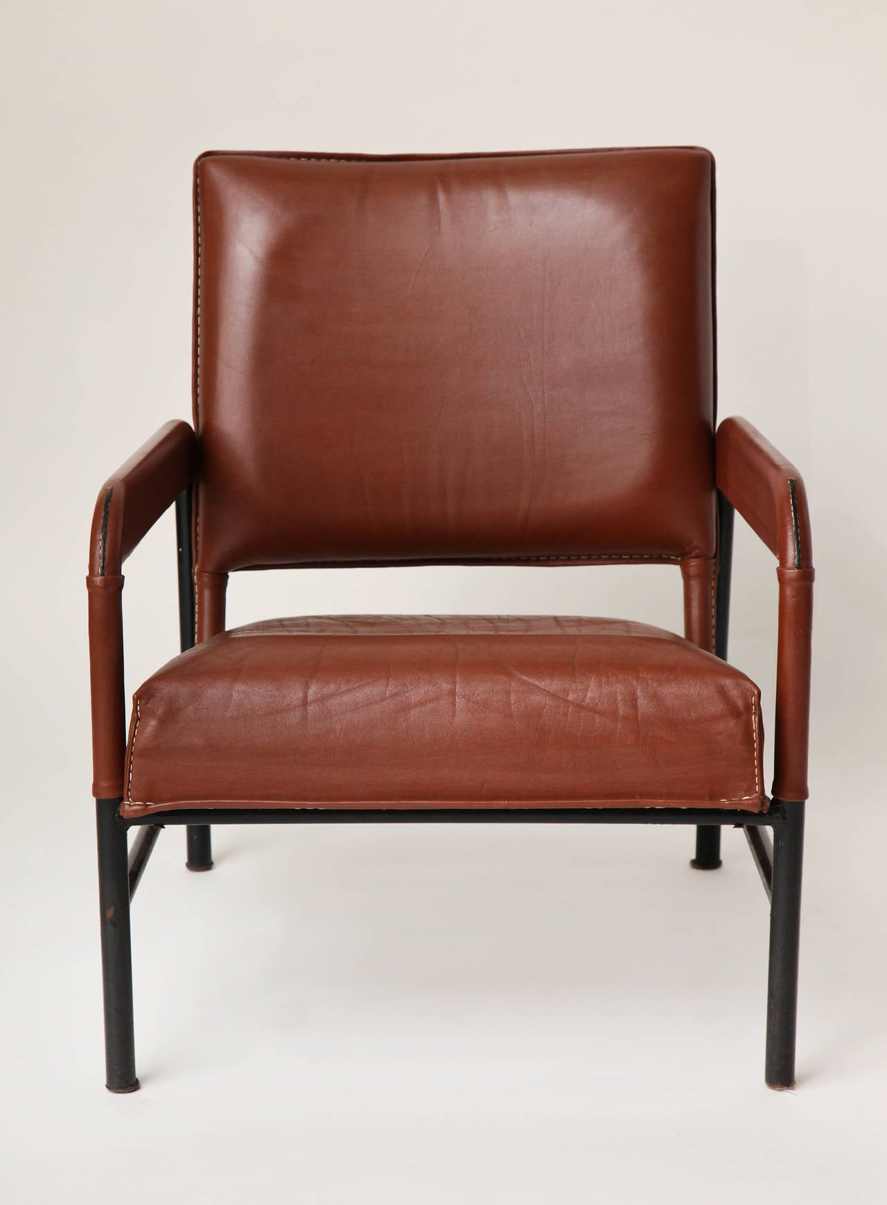 Ensemble de trois fauteuils en cuir et fonte à la manière de Jacques Adnet.