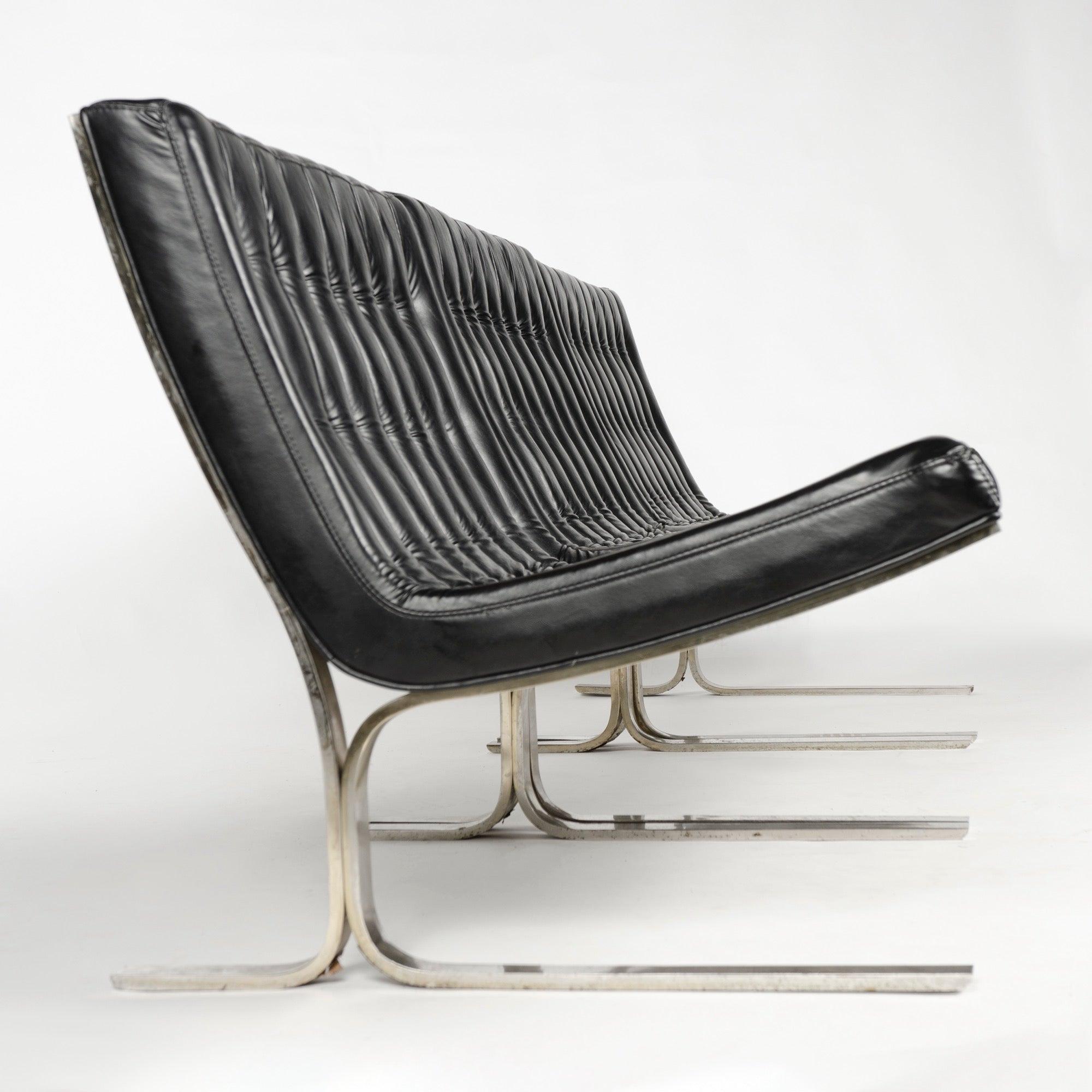 A set of three model 28 lounge chairs having rich black leather seats with deep button tufting and welt cord detailing on stainless steel frames.