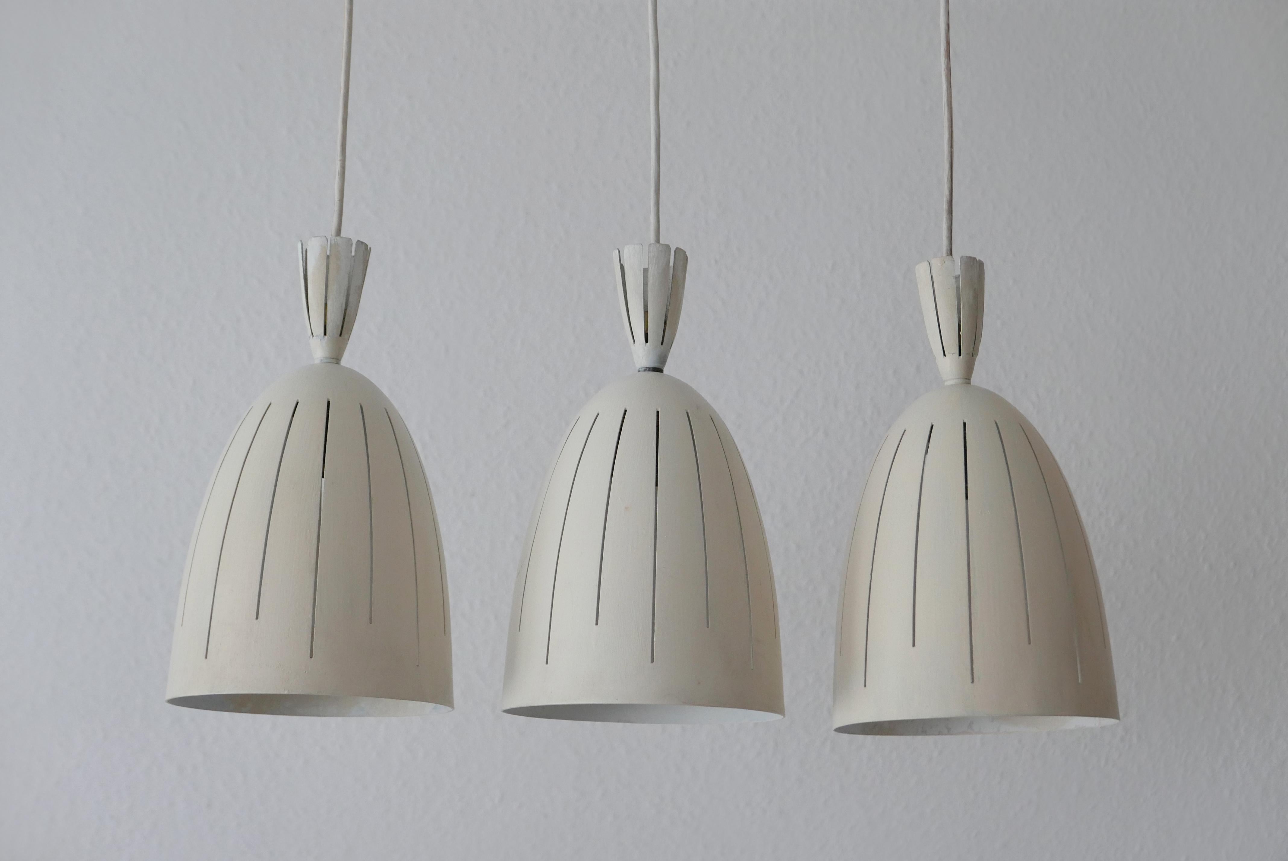 Set of three extremely rare and elegant Mid-Century Modern diabolo pendant lamps. Designed and manufactured probably in 1950s, Germany.

Executed in perforated and lacquered aluminium. Each lamp needs 1 x E27 Edison screw fit bulb, is wired, and in