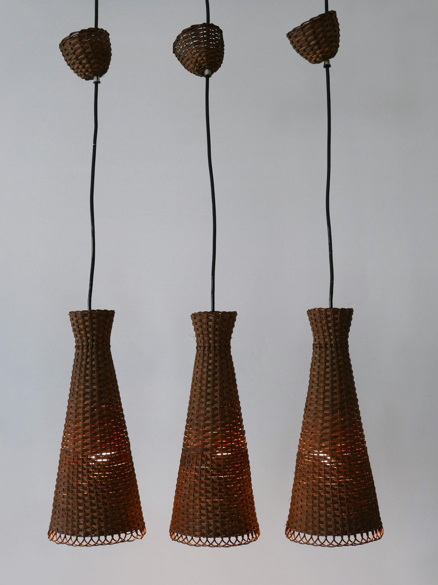 Satz von drei seltenen, schönen und sehr dekorativen Diabolo-Pendelleuchten oder Hängelampen aus der Jahrhundertmitte. Hergestellt in Deutschland, 1960er Jahre.

Ausgeführt in Rattan, jede Pendelleuchte kommt mit 1 x E27 / E26 Edison Schraube fit