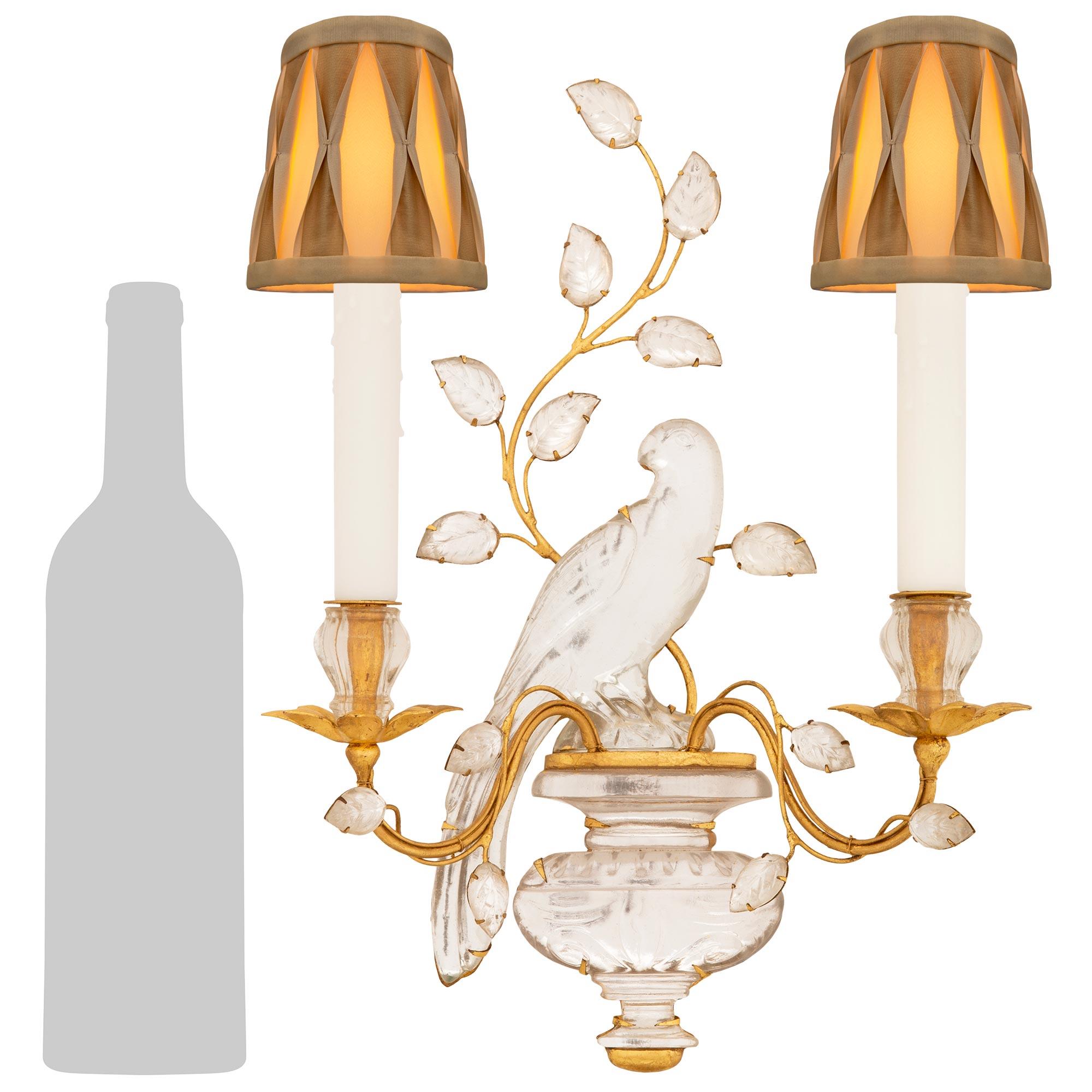 An elegant and most charming set of three French turn of the century Louis XVI st. Gilt Metal, Silvered Leaf, and Crystal sconces attributed to Maison Bagues. Each two arm sconce displays a beautiful bottom Crystal urn with a lovely mottled design