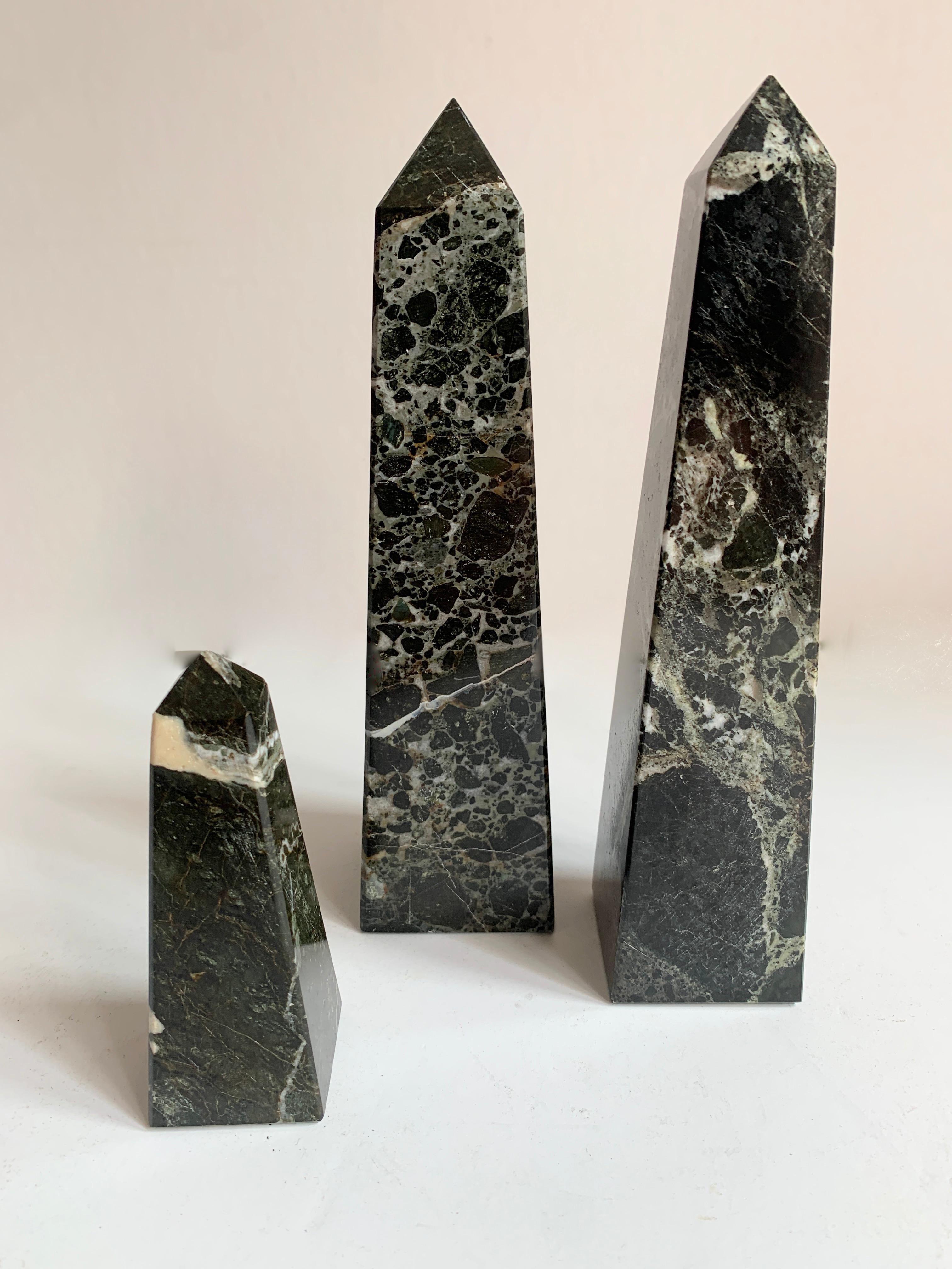 Three black marble obelisks. The trio are a nice decorative addition to the desk or shelf, however could easily be paper weights or bookends. A very nice set of three black with white veining.

Sizes: 
1.75 x 1.75 x 8