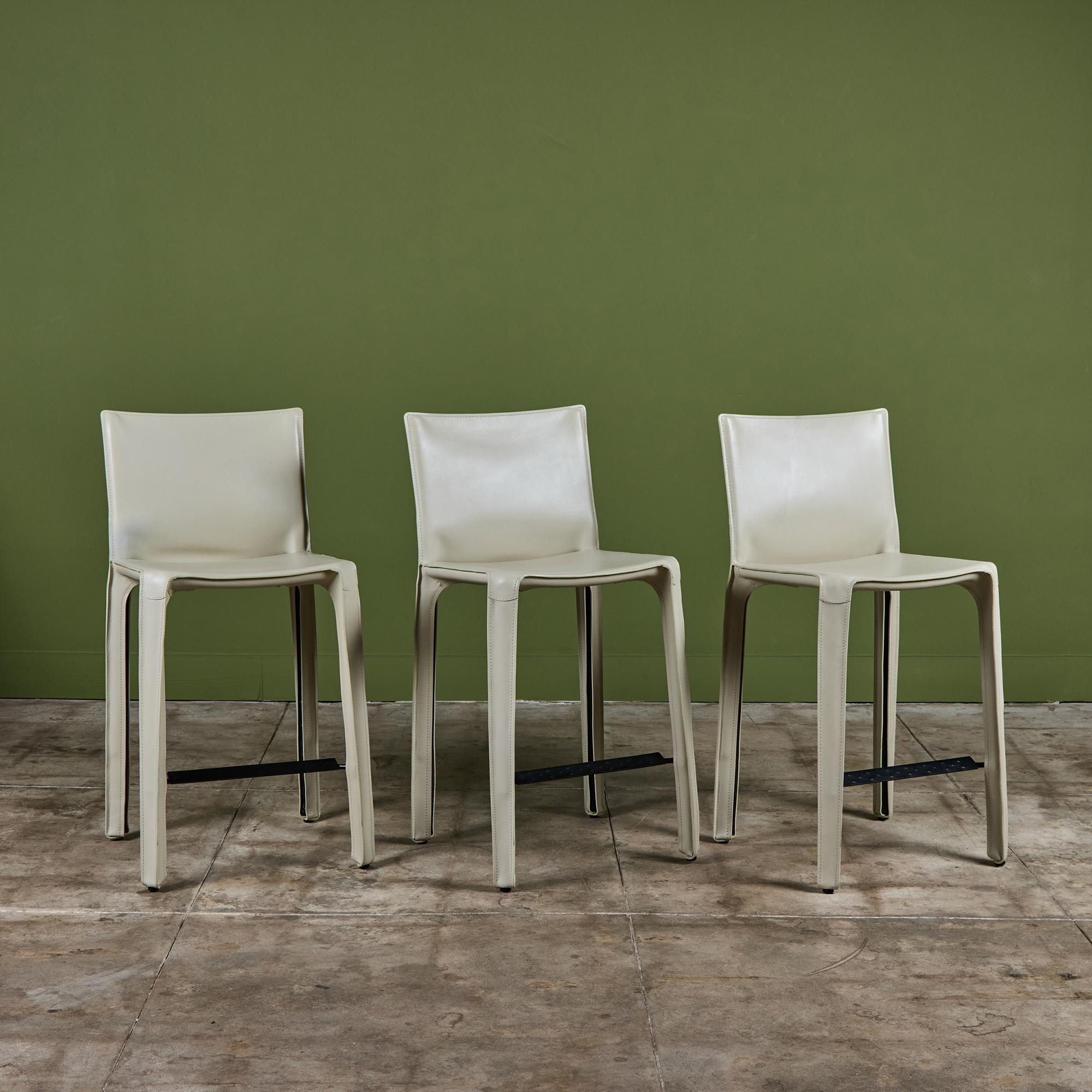 This iconic design by Mario Bellini for Cassina c.1970s, Italy, features the original chalky white saddle leather which is wrapped atop a steel frame. The back legs feature a black zippered detail. A black textured footrest runs along the front of