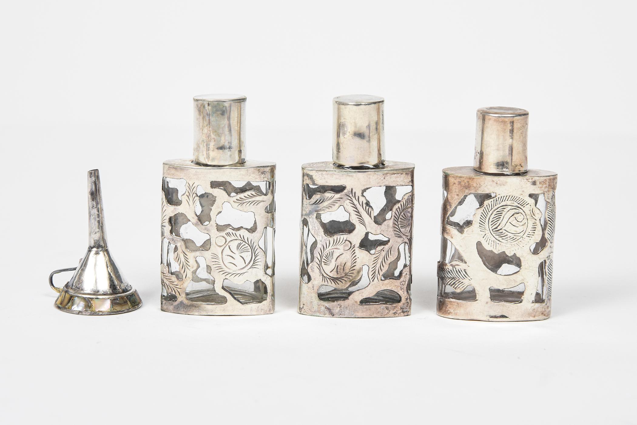 Tre bottiglie di profumo messicane in argento sterling e vetro della metà del XX secolo, con un disegno a ross e foglie. Le bottiglie variano in altezza, due sono alte 2,11' e l'altra 2