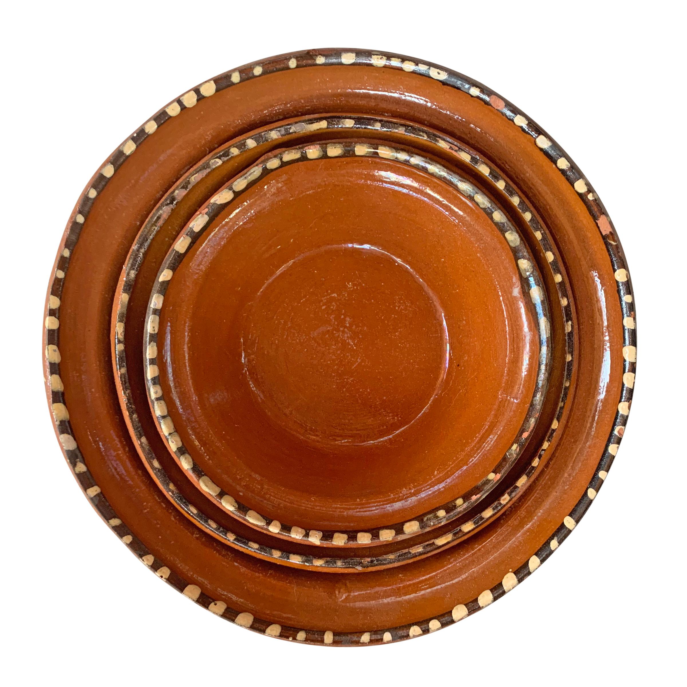 A wonderful set of three Mexican terracotta bowls in graduated size, and each decorated with a yellow and black striped rim. Bowls have a clear glaze on their interiors, and are unglazed on the exterior.

Measures: Small 6 in. diameter x 2 in.