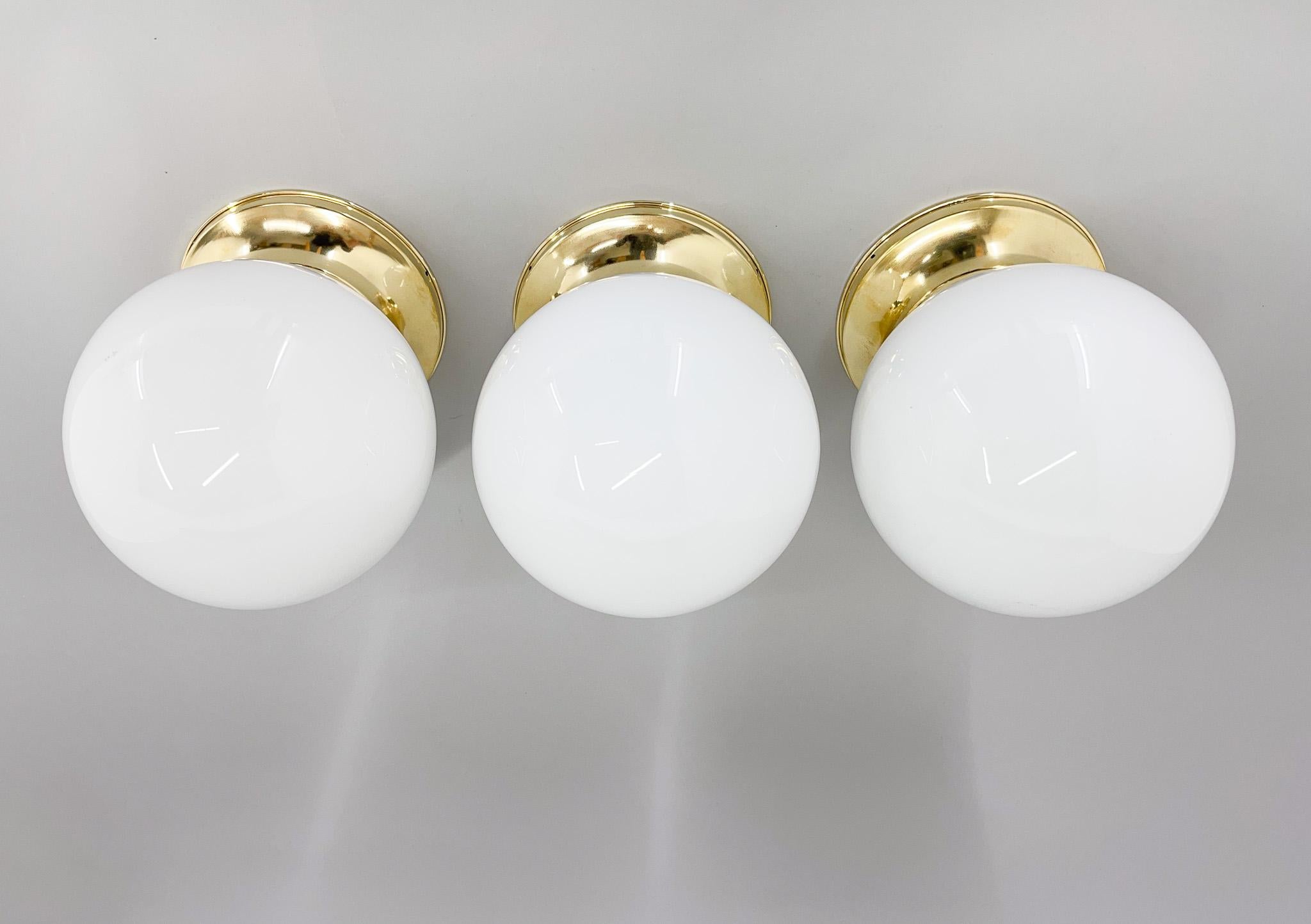 Set of three beautiful restrored brass and milk glass vintage ceiling lights. The light have been restored. The diameter of the brass base is 18 cm. Bulbs: 3x 1 E26-E27. US wiring compatible.