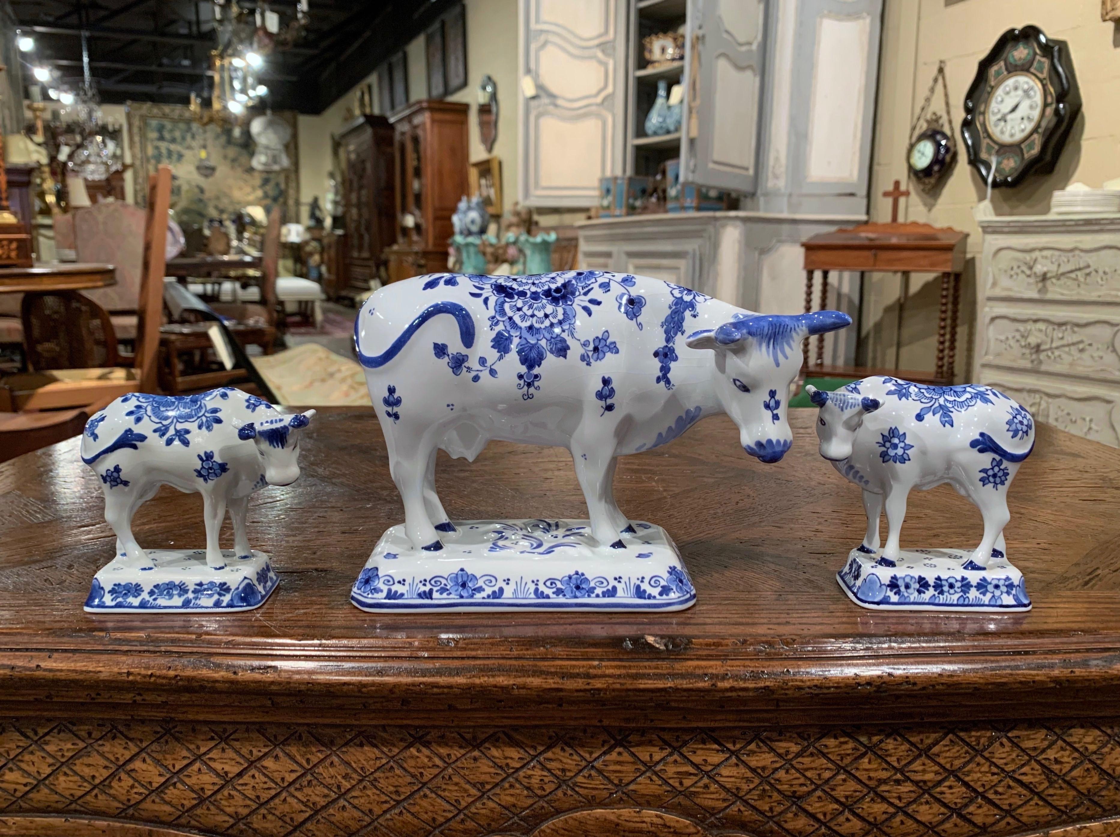 Crafted in Holland circa 1960, the three porcelain cow sculptures are hand painted in the traditional Delft blue and white colors. Each bovine figure is stamped on the bottom 