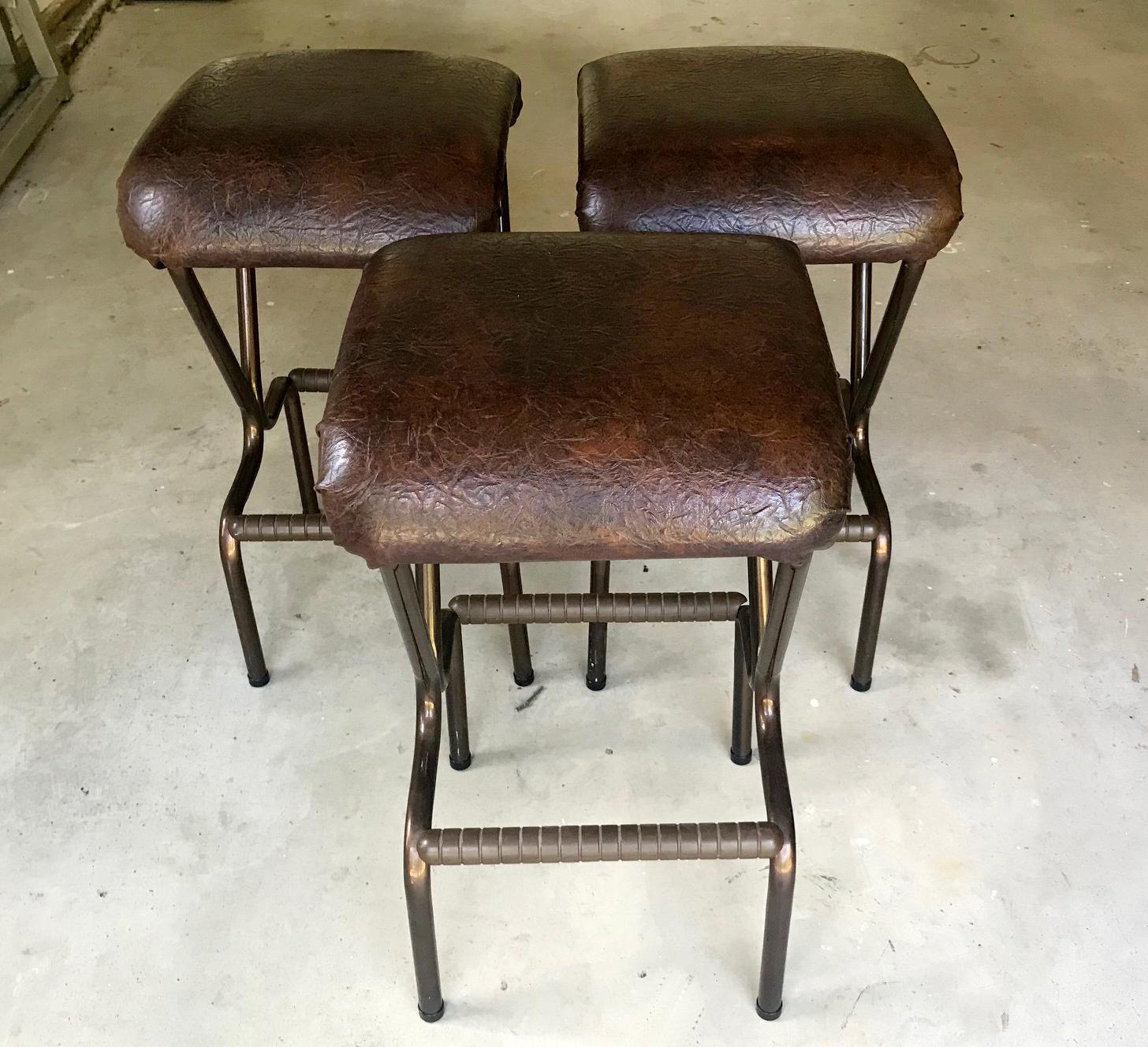 This set of bar stools were made by Daystrom, USA, circa 1960s. Tubular metal frame construction with padded seat covered in textured Naugahyde and footrests on both side. Original labels underneath. Great for period interior with an Industrial chic