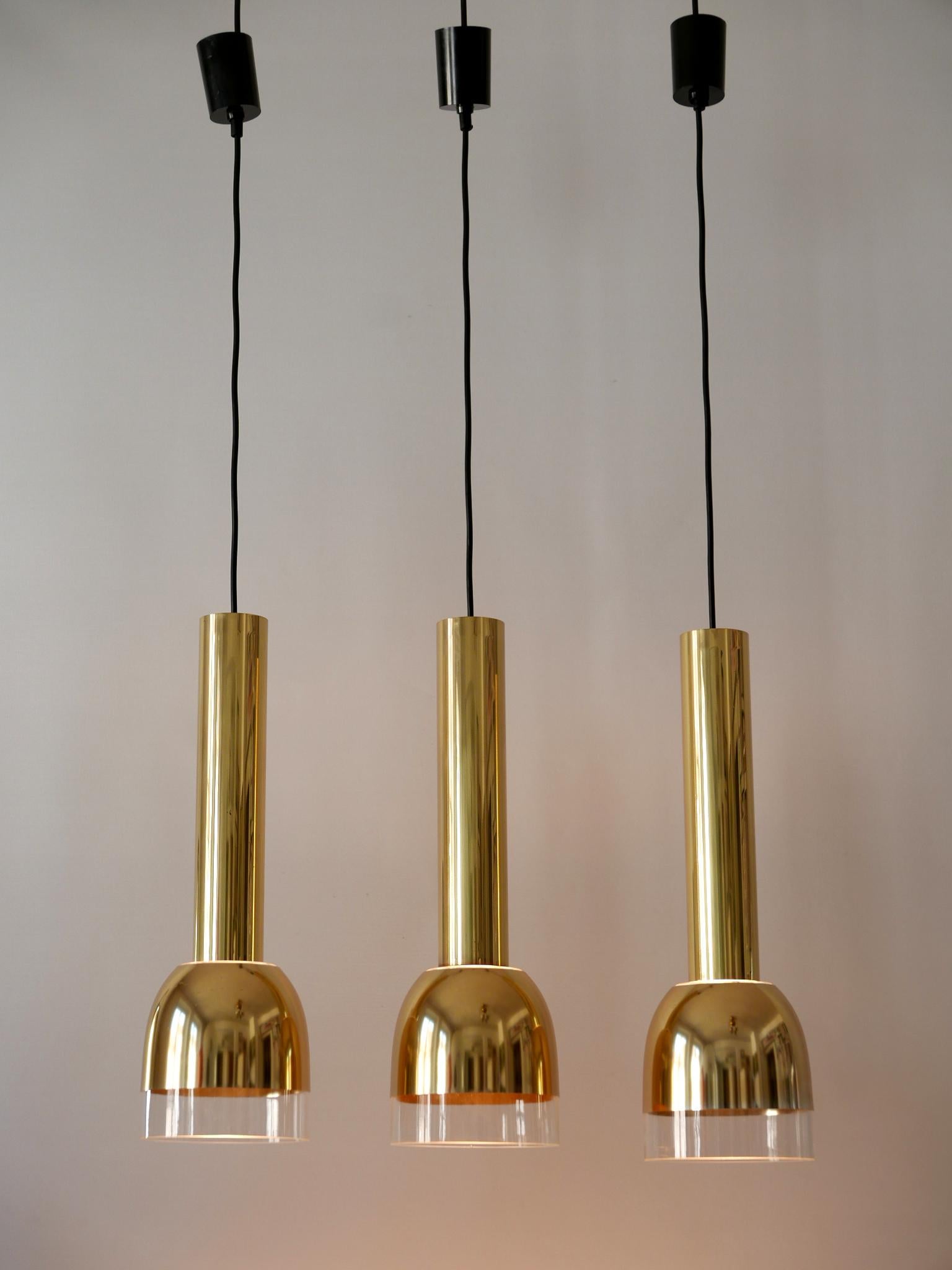 Set of three elegant Mid-Century Modern pendant lamps. Designed and manufactured by Glashütte Limburg, Germany, 1970s.

Executed in brass, gold anodized aluminium and glass, each lamp needs 1 x E27 / E26 Edison screw fit bulb, is rewired. It runs