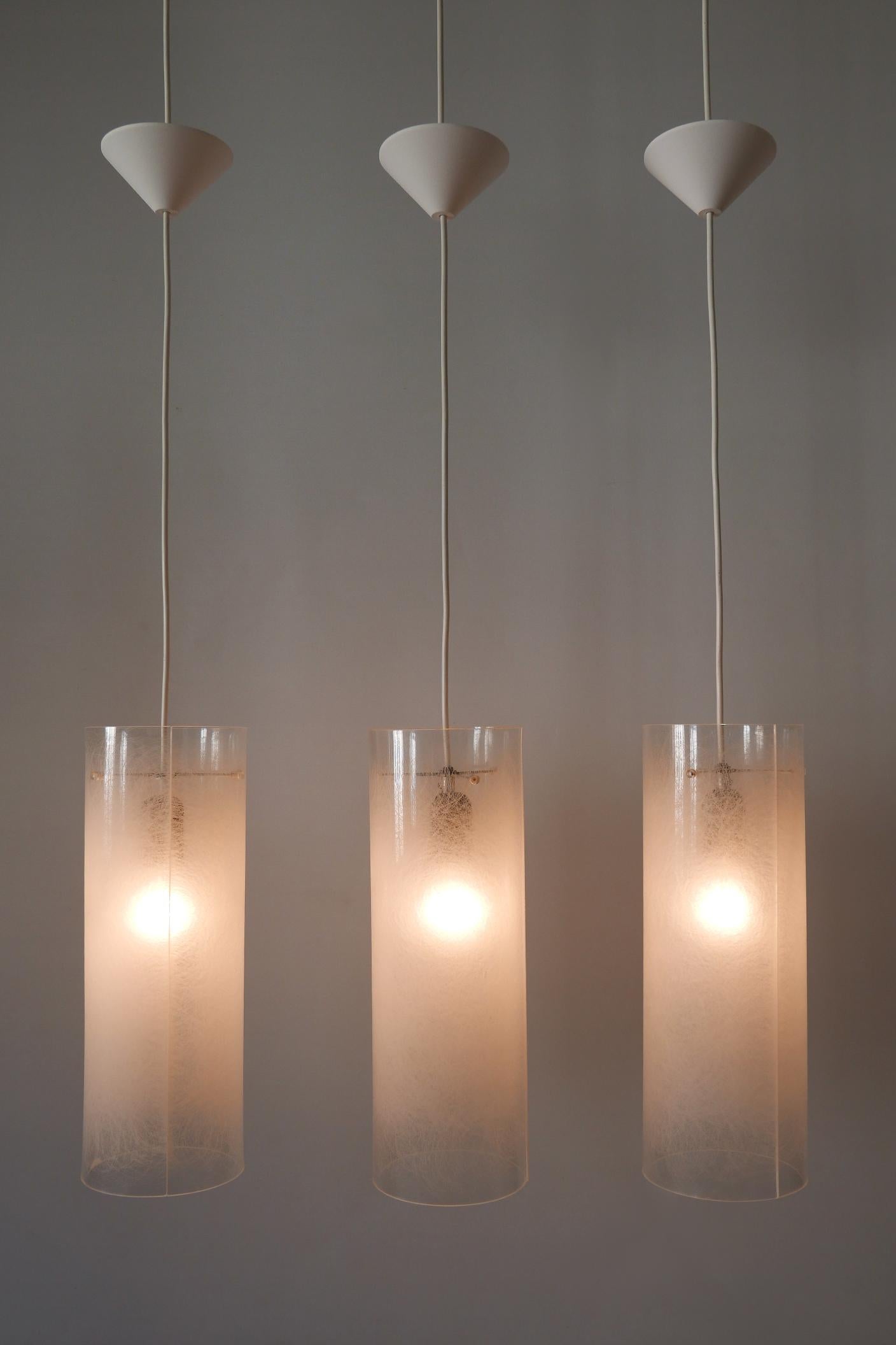 Set of three rare, lovely and elegant Mid-Century Modern pendant lamps or hanging lights. Manufactured probably by Rupert Nikoll, Austria, 1970s.

Executed in textured plexiglass and metal, each pendant lamp is executed with 1 x E27 / E26 Edison