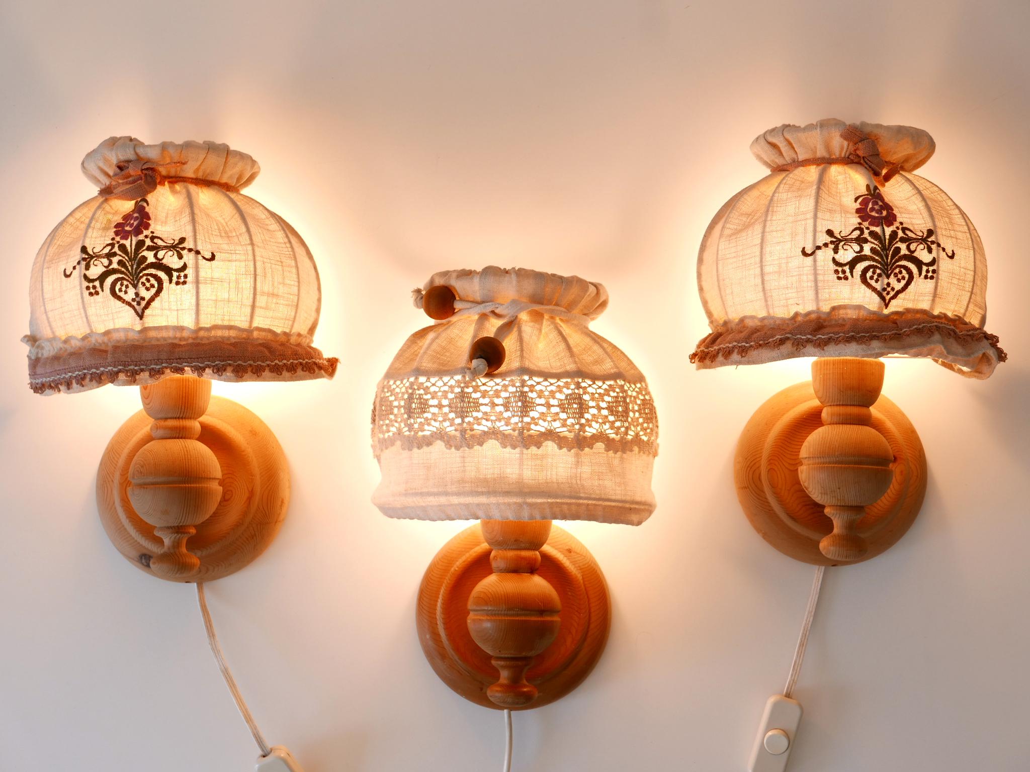 Set of three lovely and elegant Mid-Century Modern rustic sconces or wall lamps. Designed and manufactured probably in Sweden, 1970s.

Executed in pine wood and fabric, each pendant lamp has 1 x E27 / E26 Edison screw fit bulb socket, is wired and