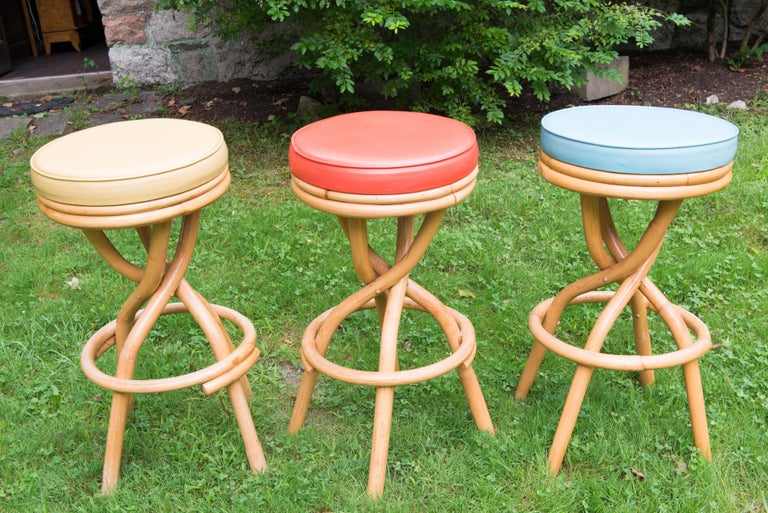 Set of 3 1950s bentwood rattan swivel stools in three different colored vinyl seats. Seats are in great condition. The rattan has a few areas where the joints are slightly separated without compromise to the structure. Fabulous looking Paul Frankl