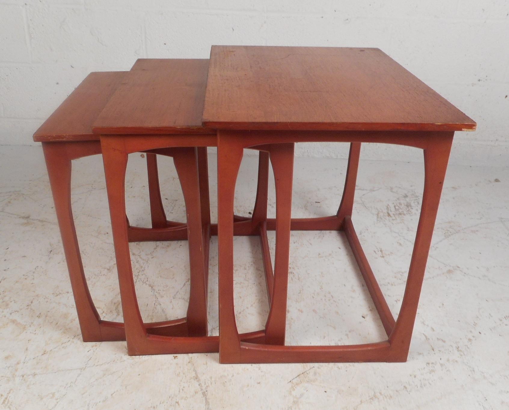 This beautiful set of three vintage modern nesting tables feature sled legs and a vintage teak finish. The sleek design allows this set to conveniently slide underneath each other for easy storage. This unique set of side tables make the perfect