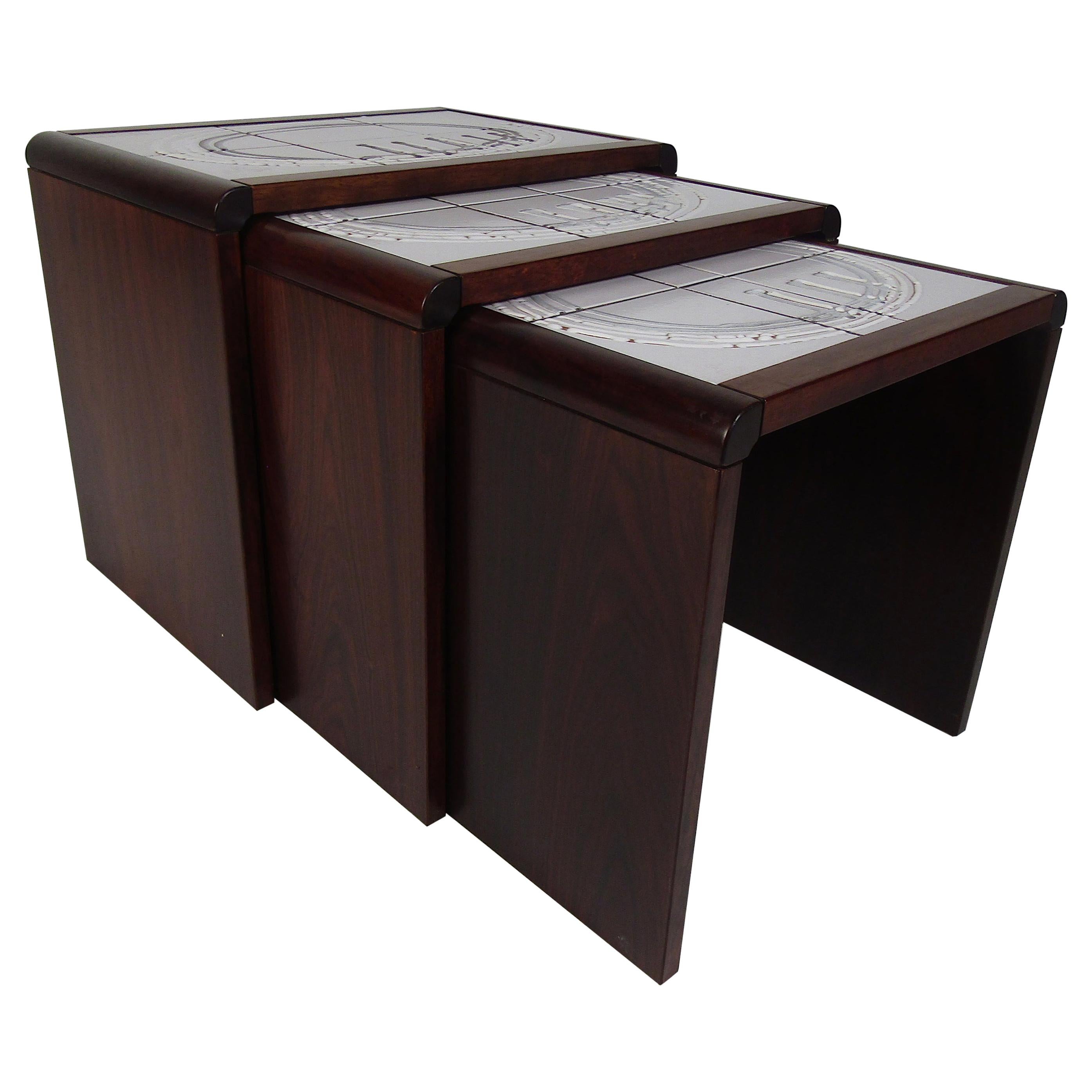 A beautiful set of three tile-top rosewood nesting tables. The unique design on the white tile-top adds to the midcentury appeal. Lovely rosewood wood grain and smooth edges make this the perfect eye-stopping addition to any modern interior. Please