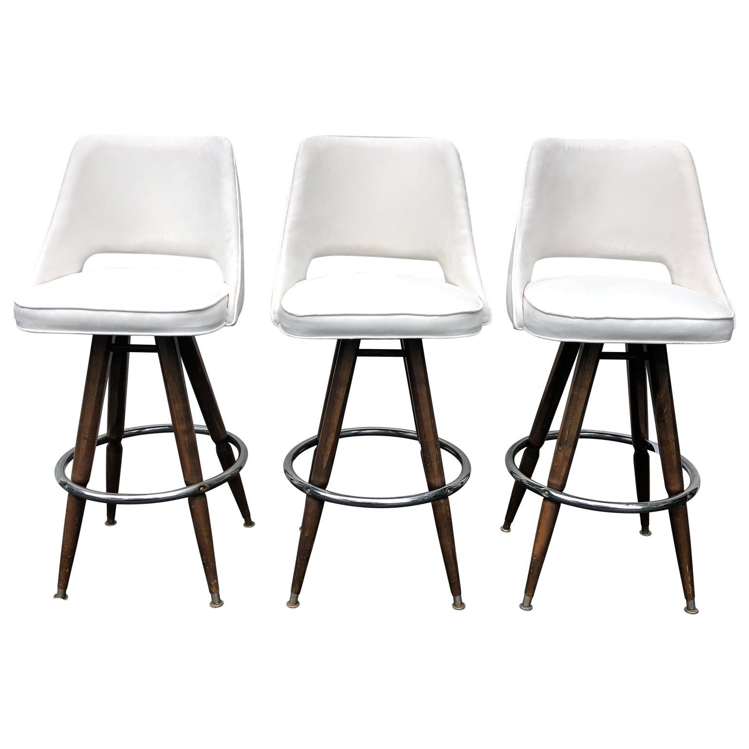 Set of three mid-century white faux-suede bar stools

3 large sturdy bar stool on wooden and chrome legs and with upholstery in white spill-proof faux suede.