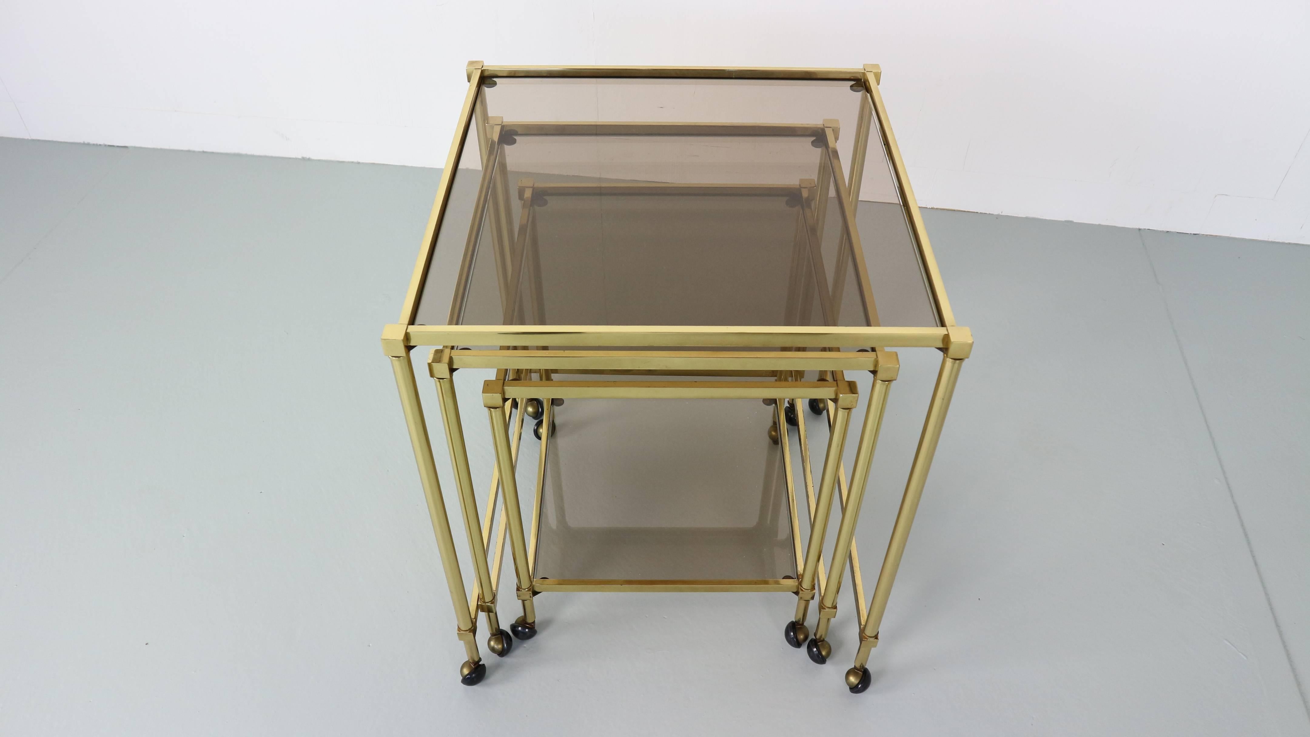 This set of three nesting tables are made from brass and glass and feature wheels. The tables can be arranged separately or can be slotted together to save space.