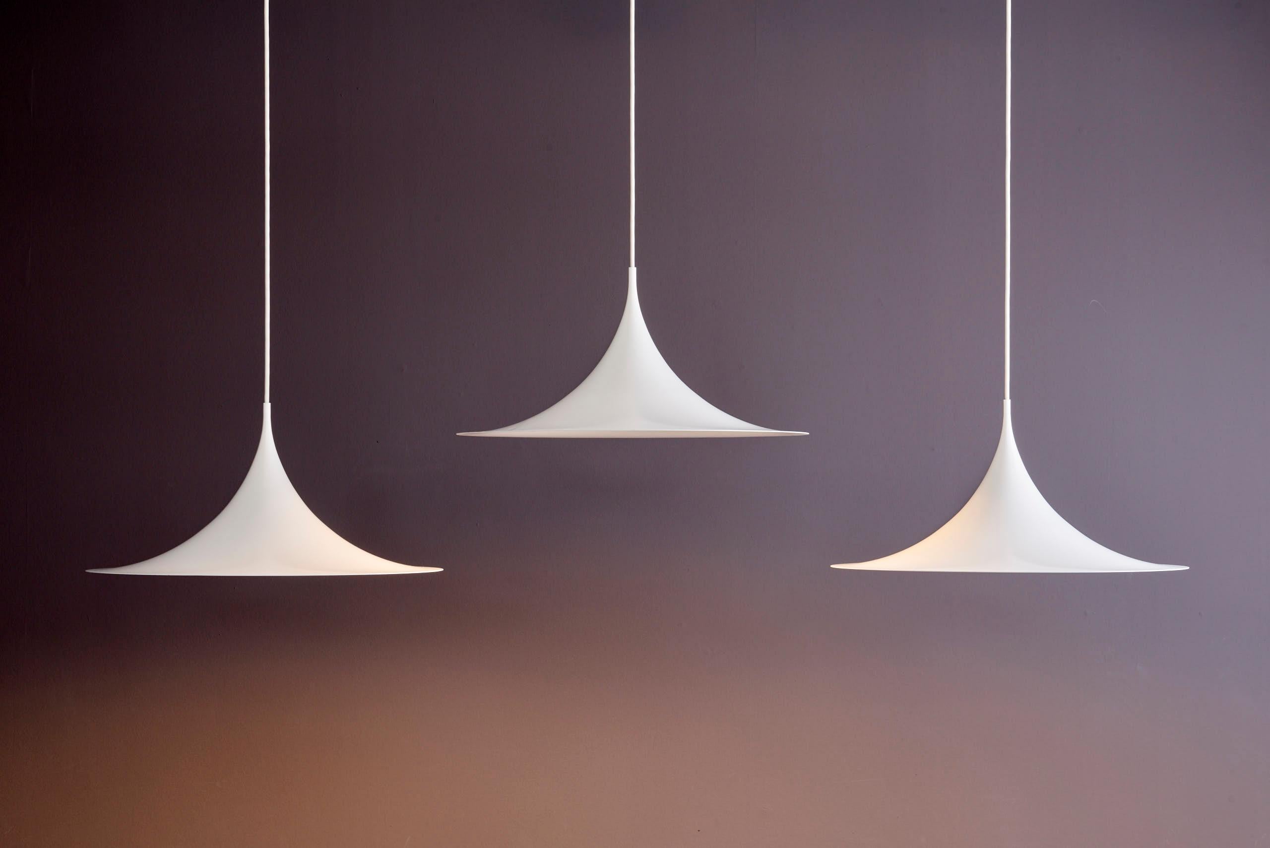 Set of three Midi Semi Pendants for Fog & Mørup. Designed by Danish architects Claus Bonderup and Torsten Thorup, the Semi pendant was introduced in 1967 as a striking counterpoint to the organic forms of the era. Its crisp, arching aluminum