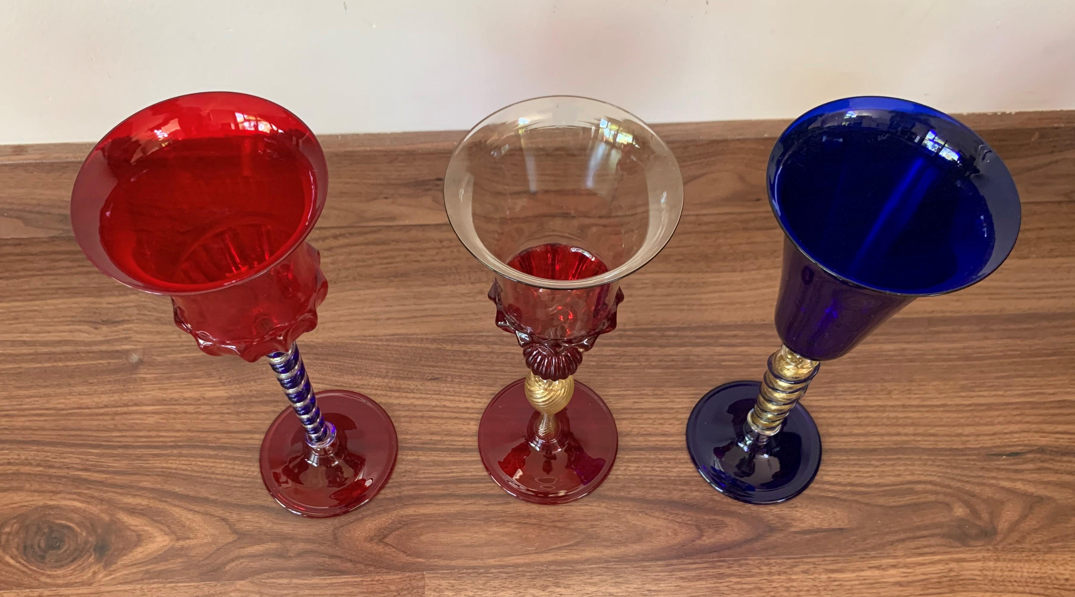 Set of three modern Murano glass goblets, completely handmade and mouth-blown.
This striking set is made of three complementary goblets, one in clear, other in red color and one in blue.
The gold stems feature a ridged pattern and are adorned by a