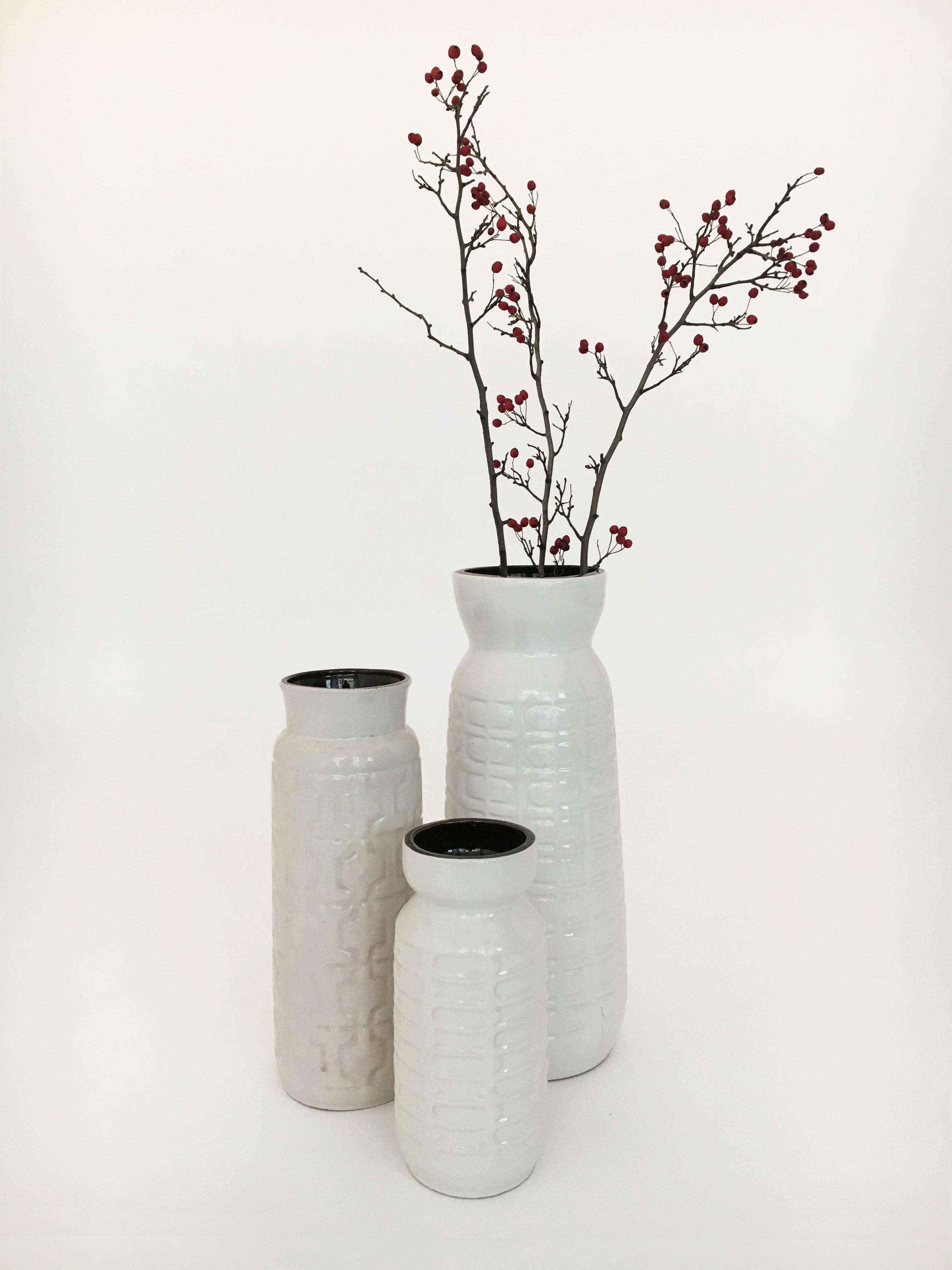 Beautiful set of three large Austrian pottery vessels vases, amazing glazes, in all modernist white, with a variations of minimal patterns on the outside. Contrasting dark brown glazed on the inside of the vessel, adding another layer of visual