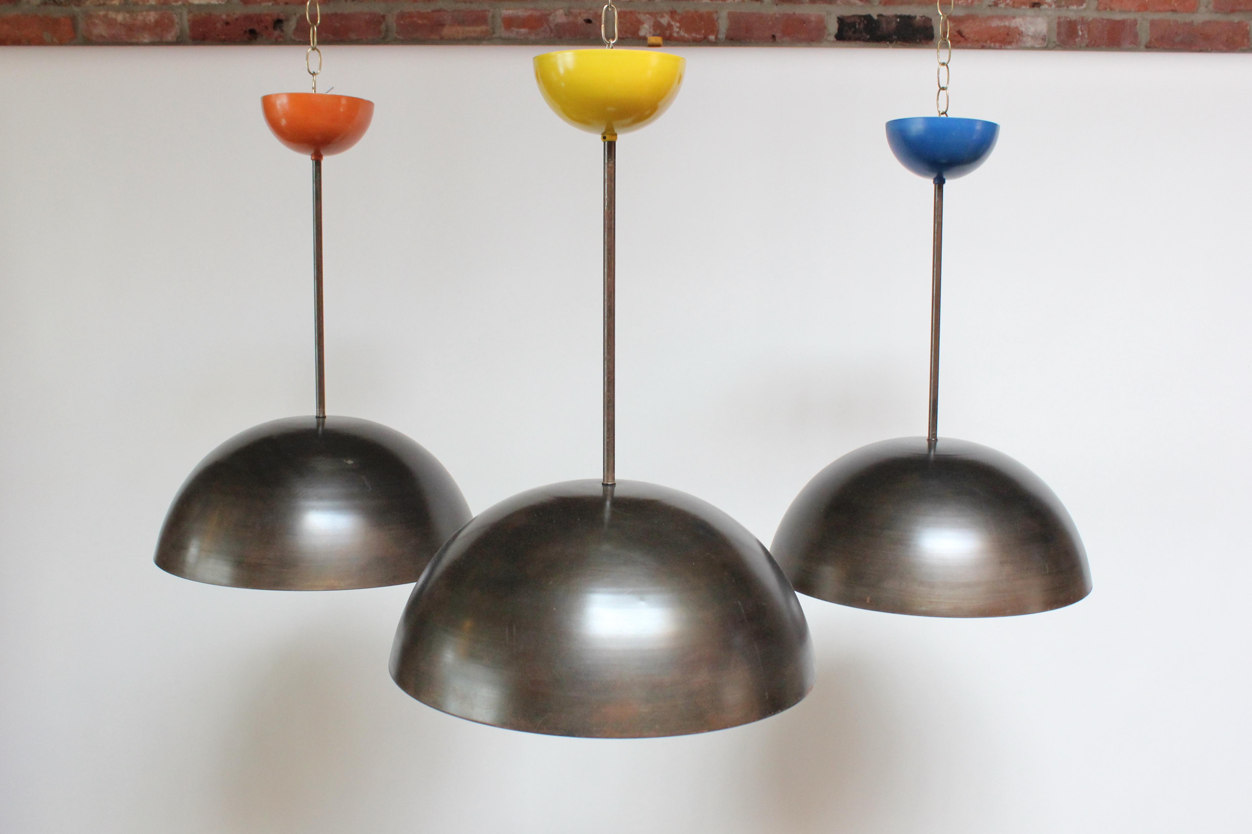 Set of three contemporary dome pendants designed and built by Brooklyn, NY Industrial designer and artist, Scott Behr (circa 2010). Feature a blackened steel hood which appears almost bronze in in color with colorful canopies and corresponding