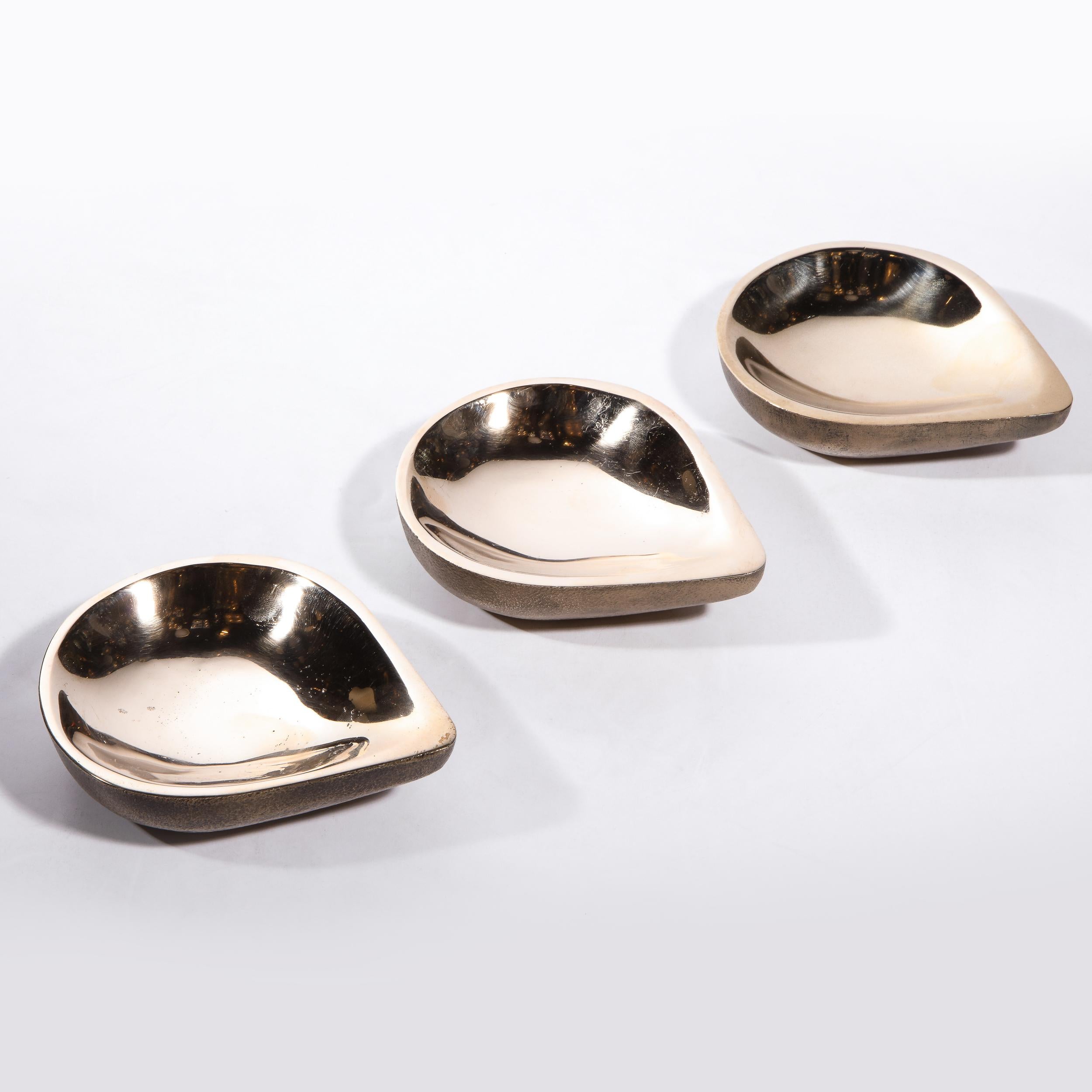 This stunning set of three modernist bronze teardrop form decorative bowls by the esteemed artist Steven Haulenbeek. They offer austere tear drop silhouettes with matte exteriors and lustrous polished interiors. This object represents one of the few