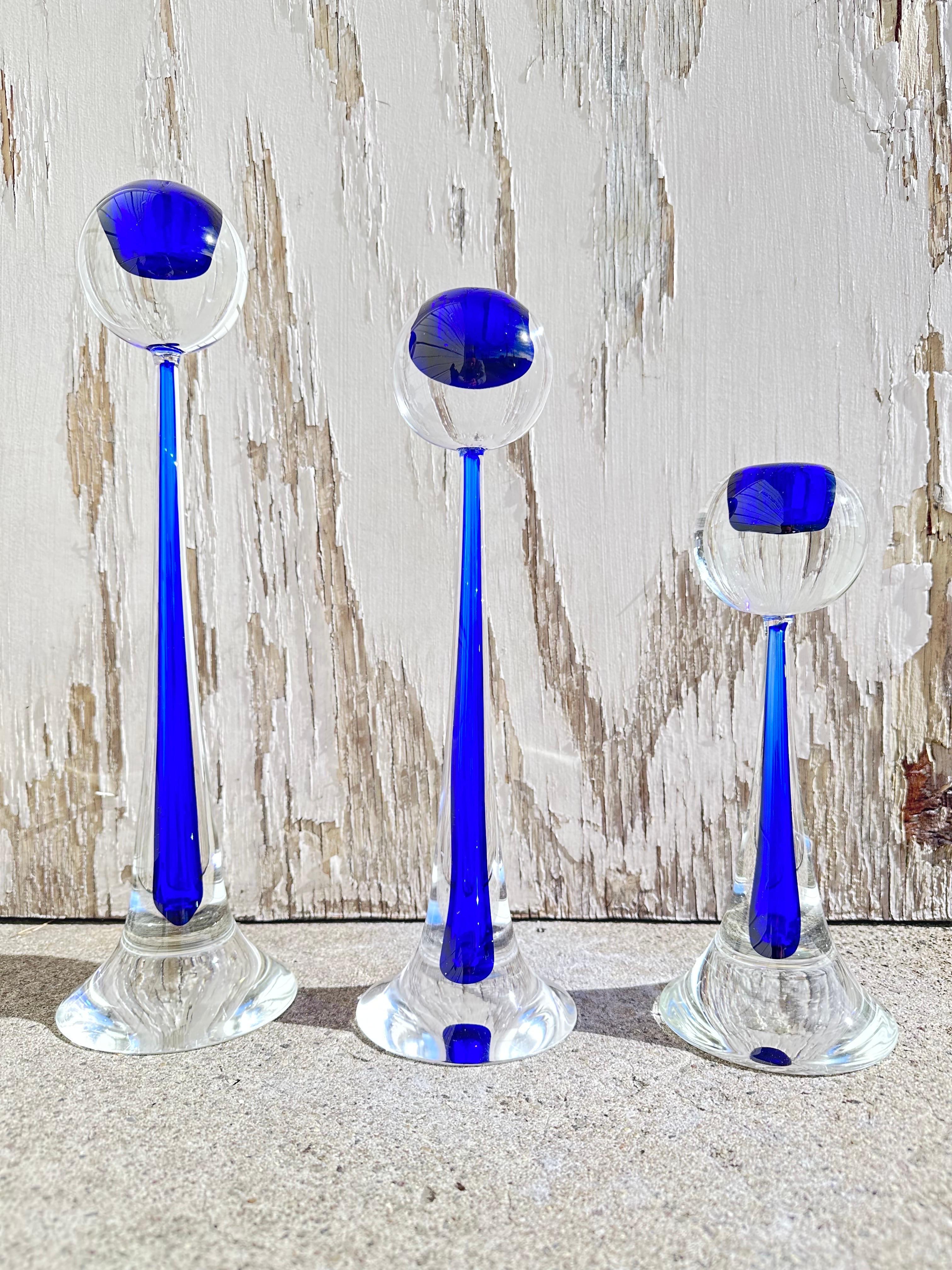 A Set of three stunning midcentury Modernist hand blown Murano glass candlesticks signed by Cenedese. These candlesticks feature a tapered teardrop design made of hand blown Murano glass. Each candlesticks form features a spherical topper that is