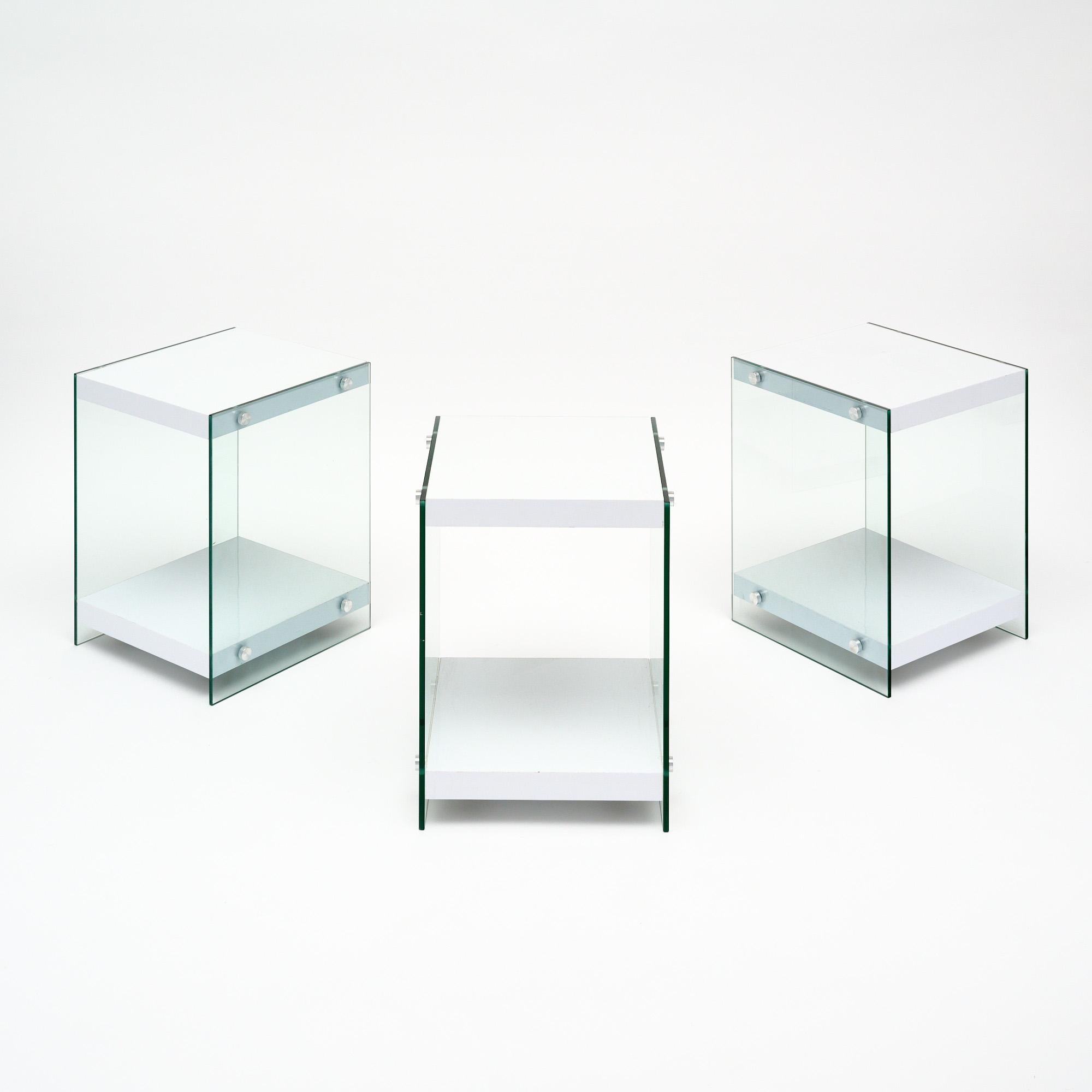 Satz von drei Beistelltischen aus Frankreich im modernistischen Stil. Jeder Tisch wird von Glasseiten mit verchromten Endstücken getragen, die das Glas an weiß lackierten Regalböden befestigen. Diese Tische sind in sehr schönem Vintage-Zustand mit
