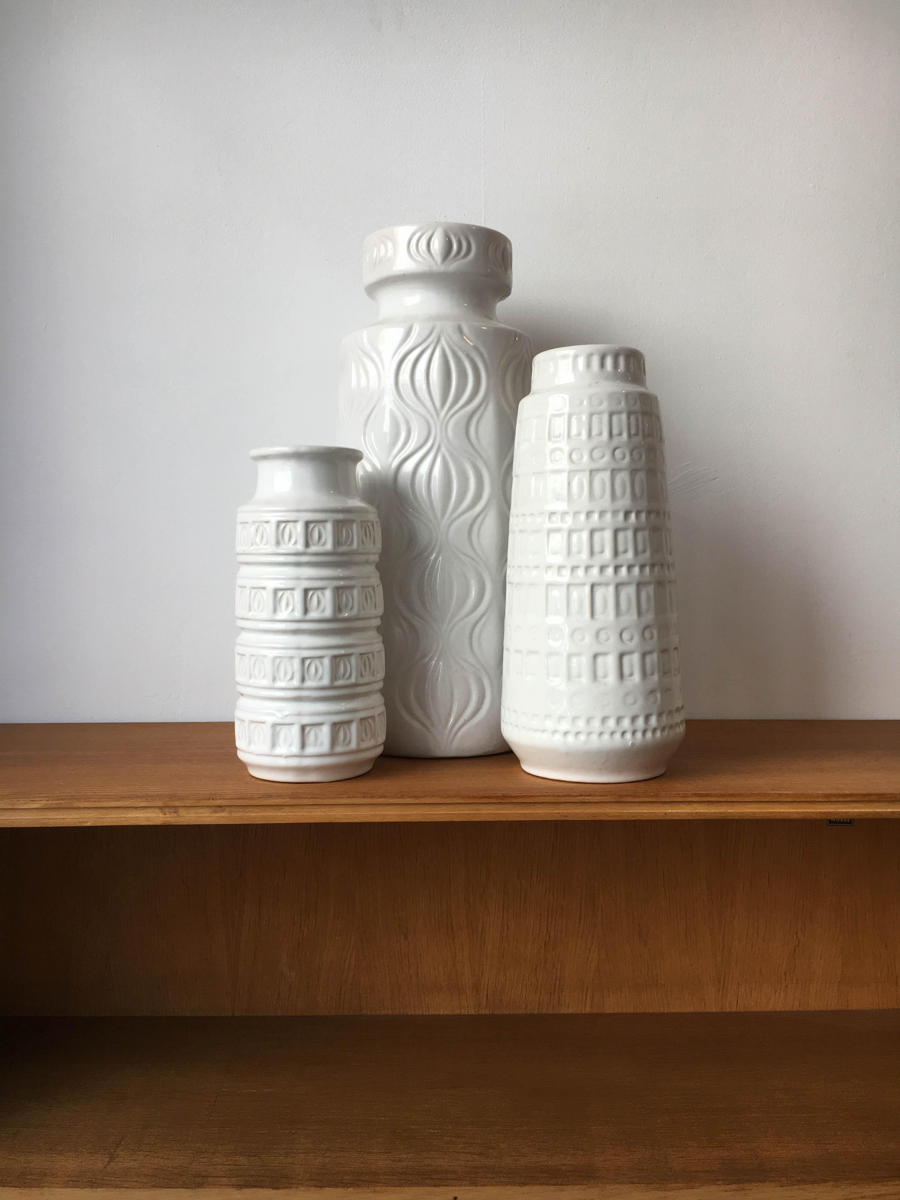 Set of three West Germany pottery vessels or vases, in all modernist white, with a variations of minimal patterns on the outside, Germany, 1960s.