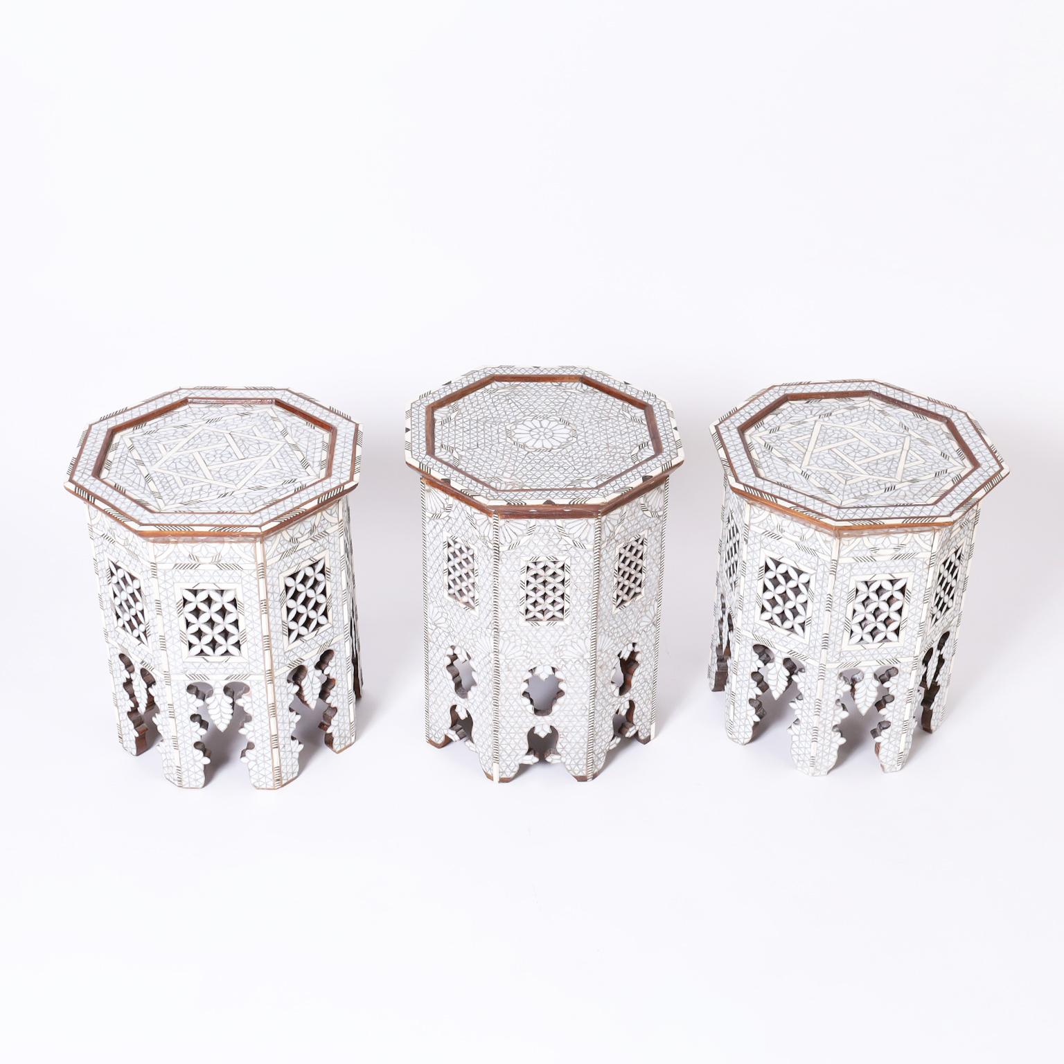 Striking set of three Moroccan stands with octagon forms crafted in walnut featuring elaborate mother of pearl geometric and floral mosaics highlighted with bone and ebony, all on classic moorish arched designs. Priced Individually.

The pair: H: 18