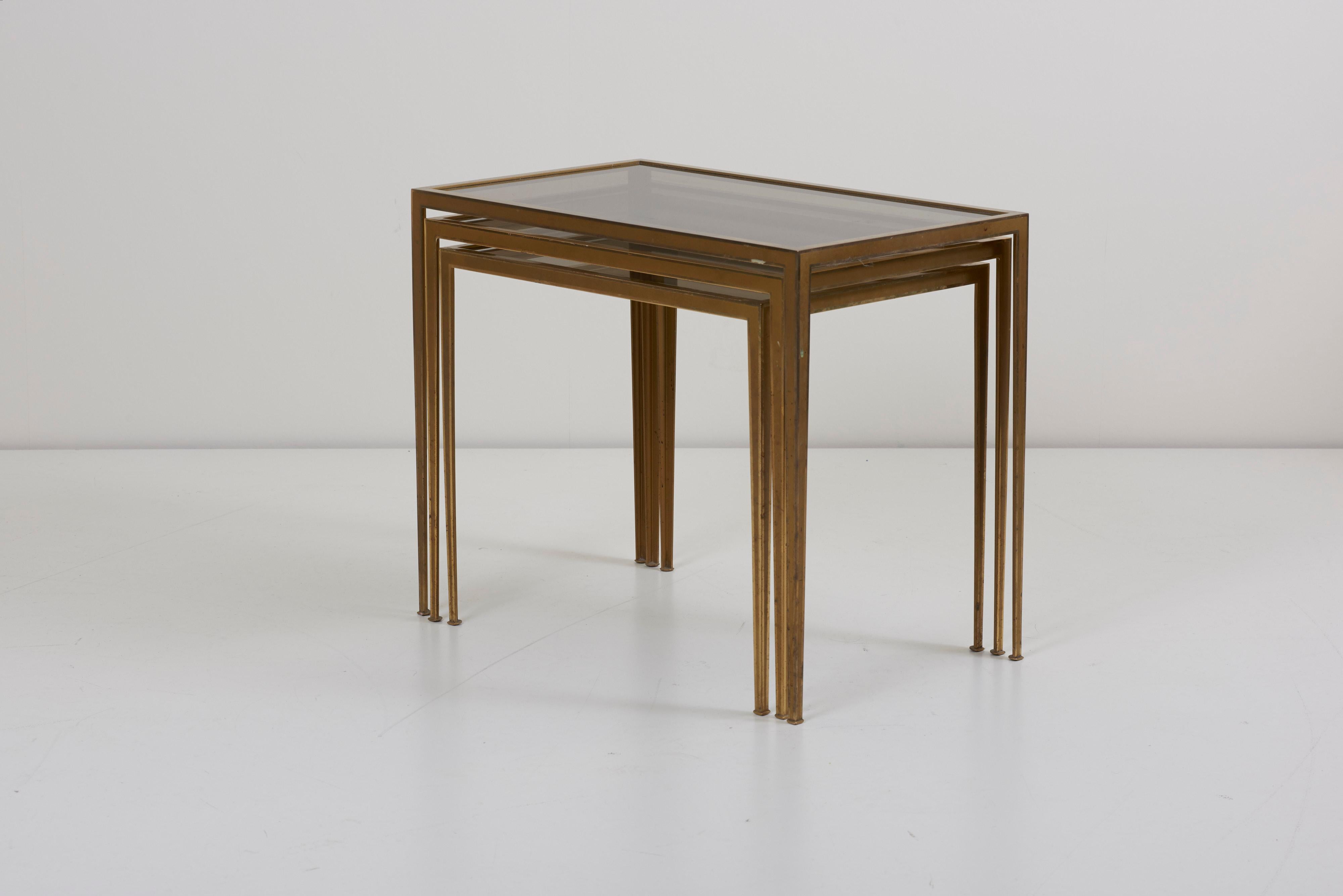 Wonderful set of three brass nesting tables with glass tops in very good vintage condition. The table legs in tapering shape providing elegance and lightness to the tables. Measurements show the biggest table.