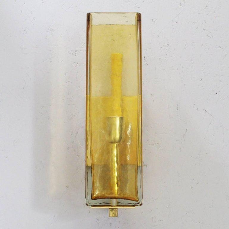 Striking set of three Italian sconces from the 1980s, each featuring hand-blown Murano glass rectangles in a warm amber tone. The glass elements are crafted in a textured finish that beautifully diffuses light, mounted on elegant brass hardware.