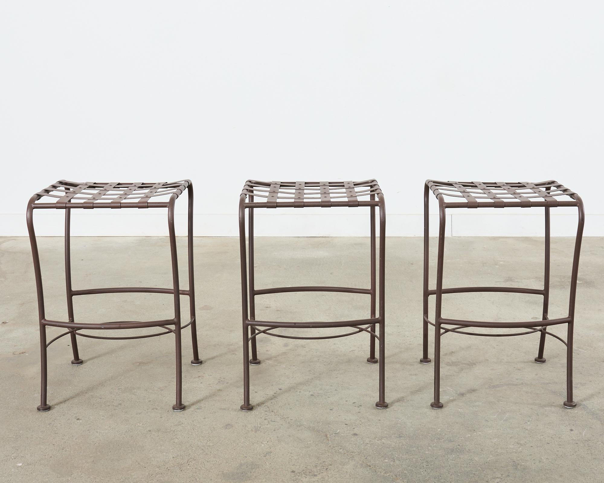 Handsome set of three wrought aluminum barstools featuring a neoclassical style lattice strap seat. Made in the midcentury style of Mario Papperzini and John Salterini. The aluminum has a powder-coated finish in a patinated metal tone to mimic aged