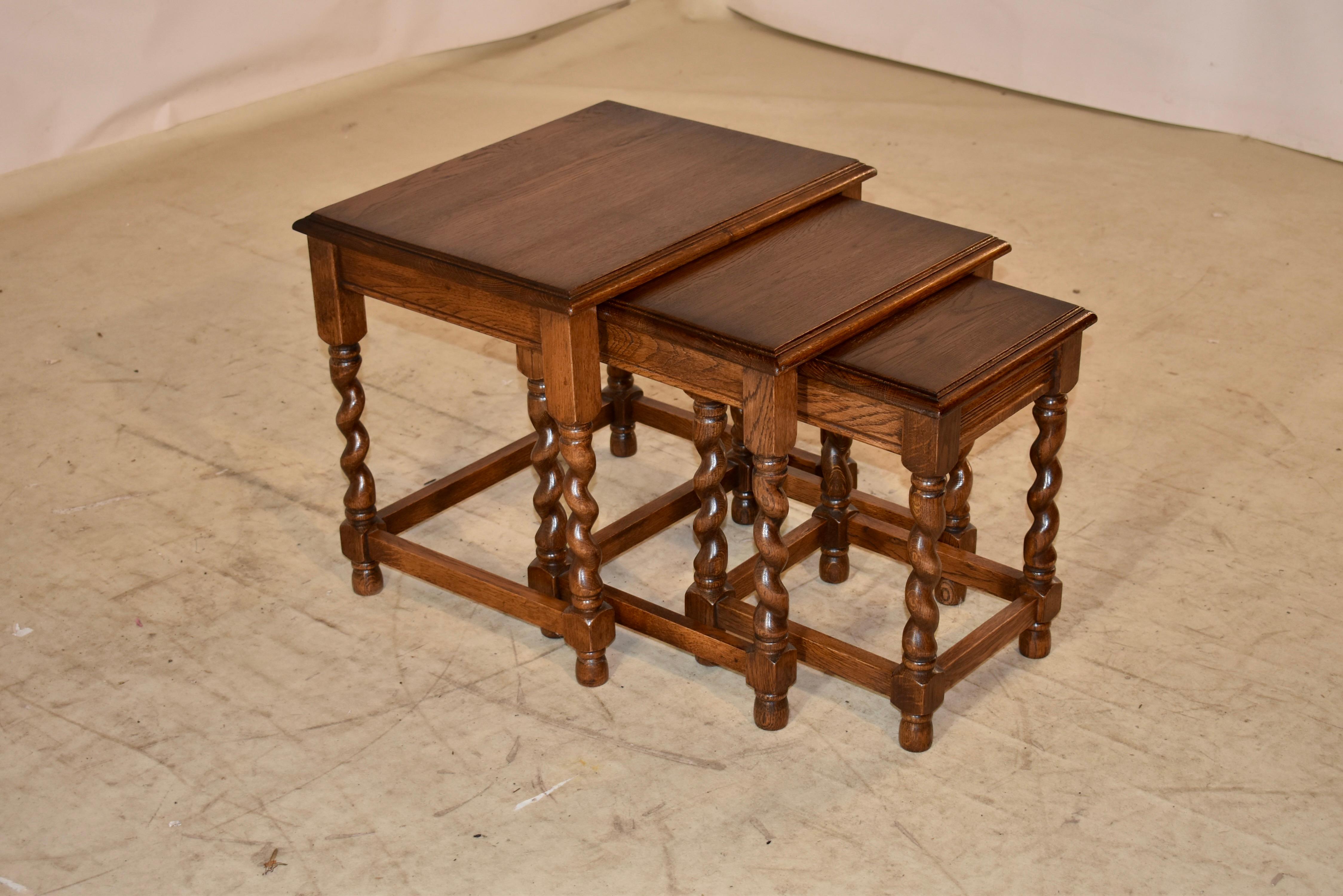 Edwardian set of three nesting oak tables from England.  The tables have beveled edges around the tops, following down to simple aprons, and are supported on hand turned barley twist legs, joined by simple stretchers.  The smallest table measures