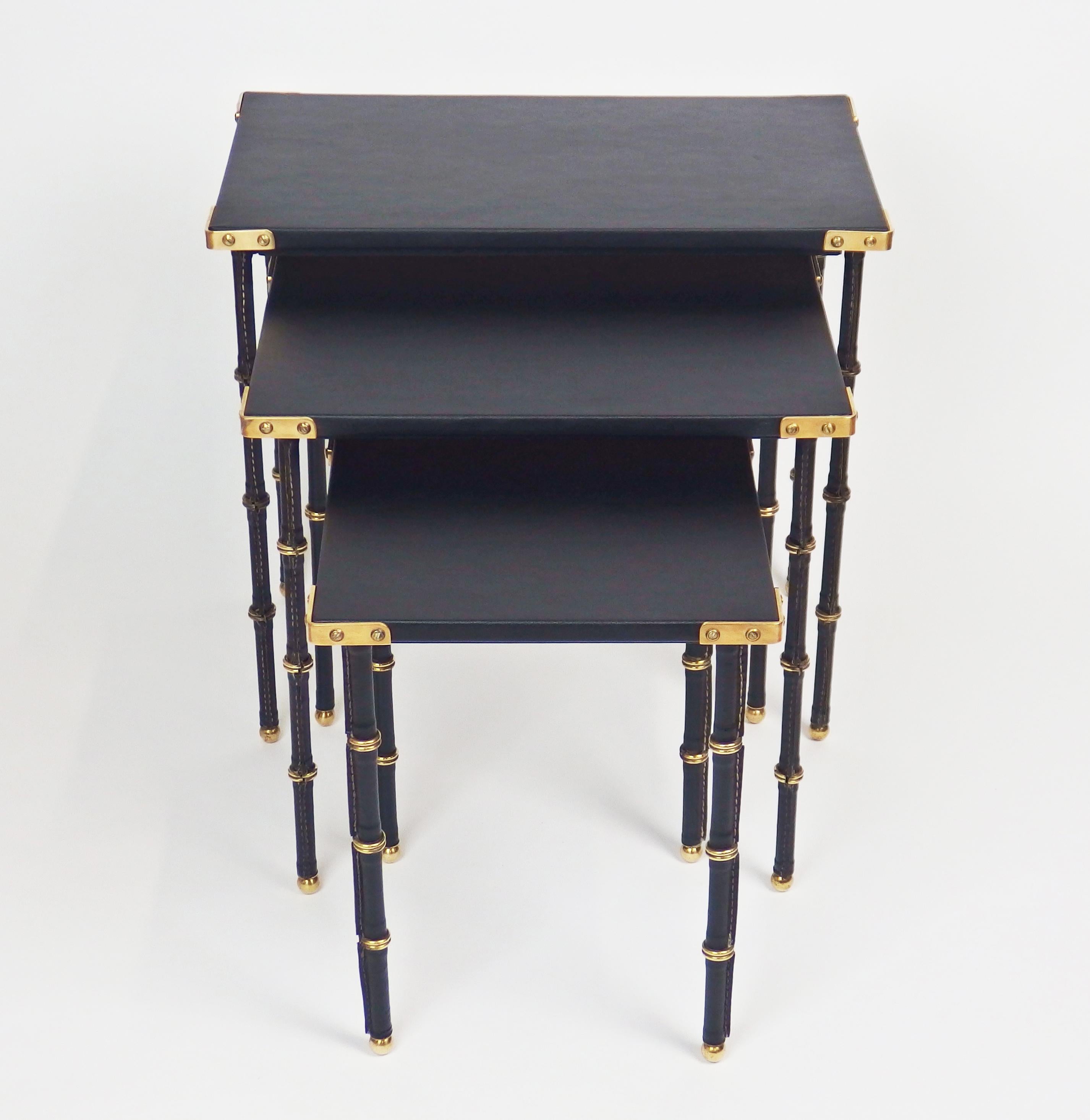 Three nesting tables by Jacques Adnet. Feet sheathed in black leather hand-stitched piqué sellier and a moleskine covered top with bronze corners.
Small table dimensions: Length 11.73in, depth 11.73in, height 14.56in.
Middle table dimensions: