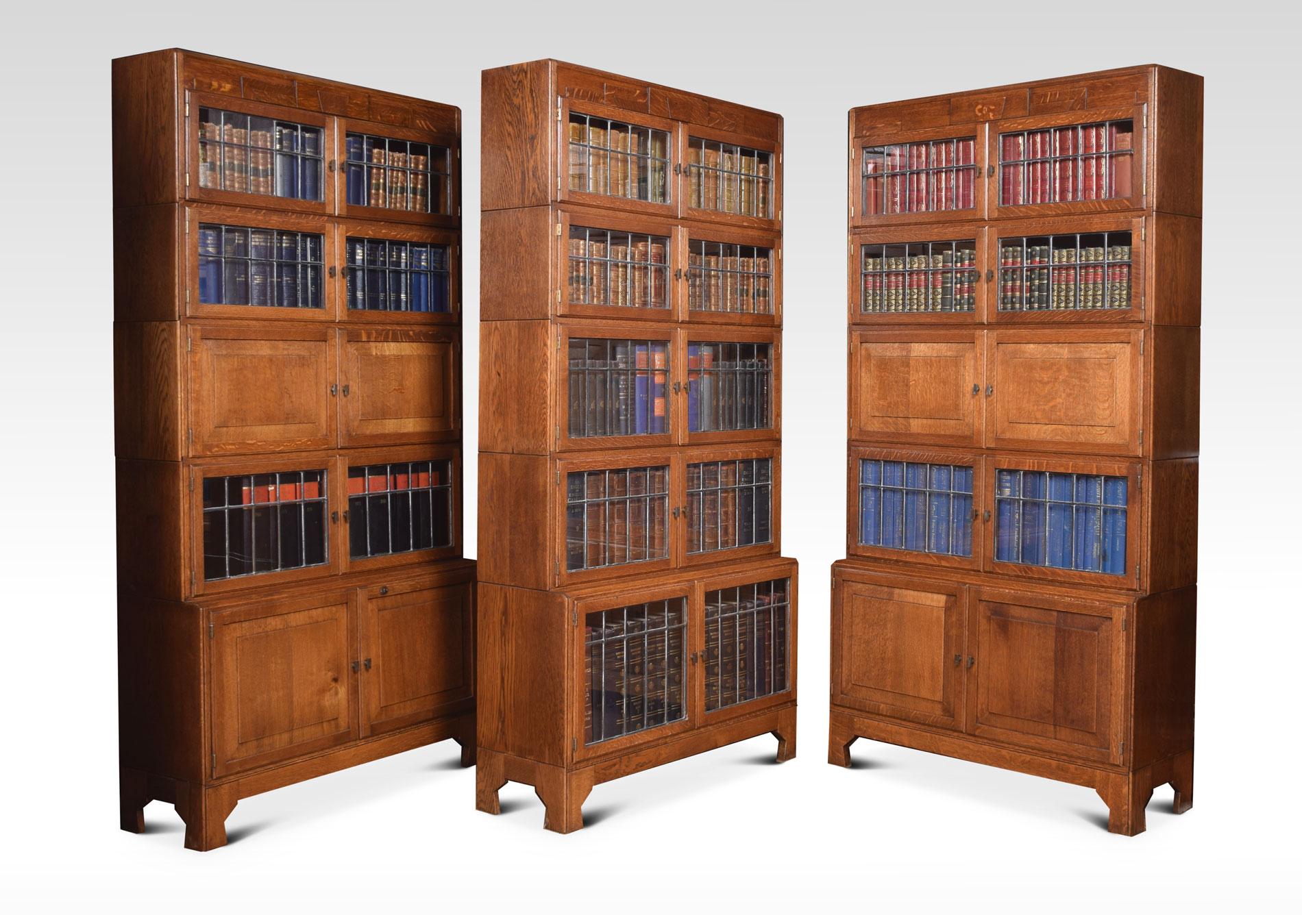 Set of three oak sectional bookcases, all having stylized Art Deco moulded tops, above an arrangement of leaded glass sections and two bookcases fitted with two cupboards. All raised up on bracket feet
Dimensions
Height 68.5 inches
Width 35.5