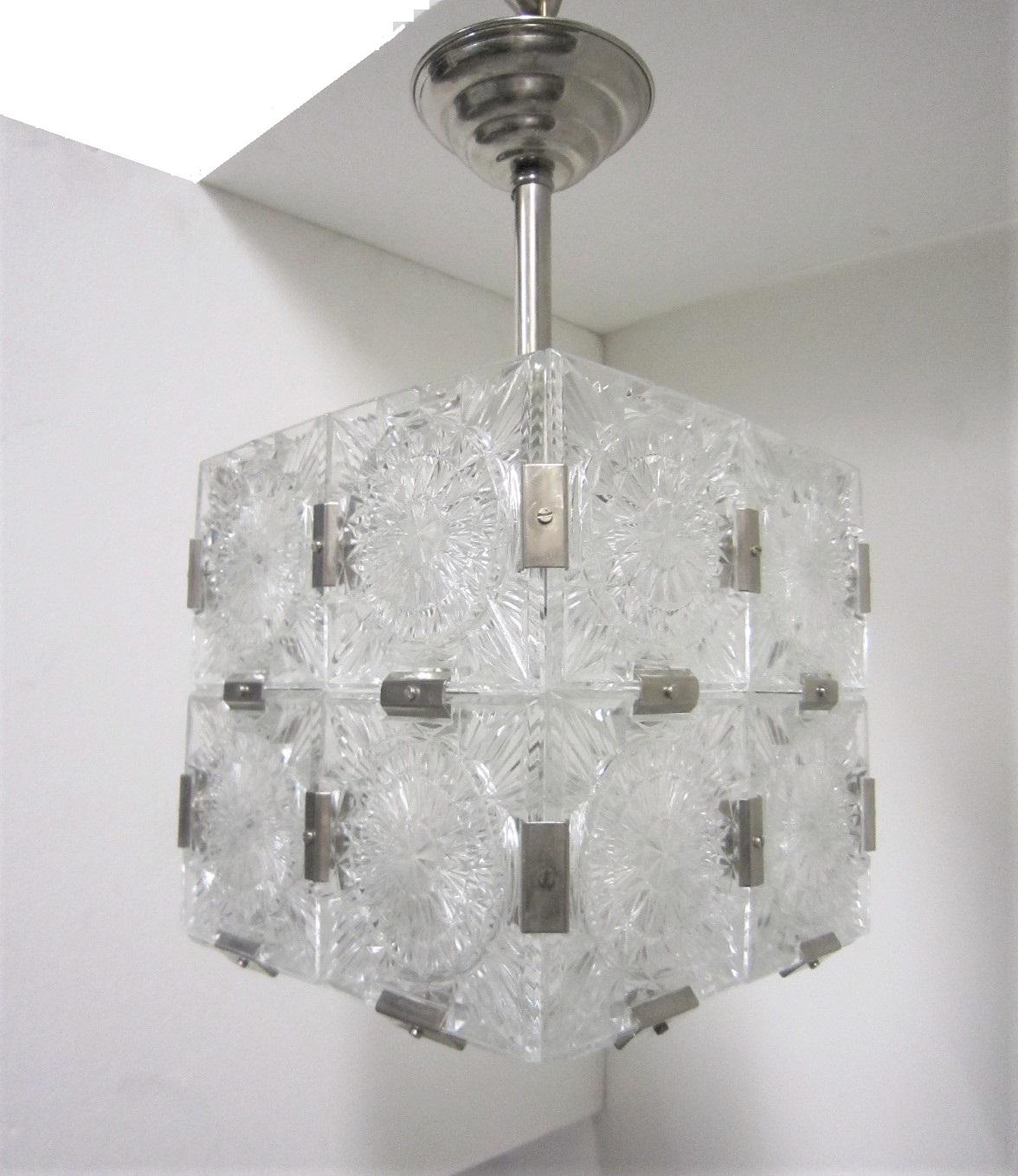 Multiple pendant squares available. Priced here as a set of three.
Modernist square chandeliers comprising 20 squares of cut-glass in two tiers formed together with original nickeled bronze brackets. The juxtaposition of the circular patterns in