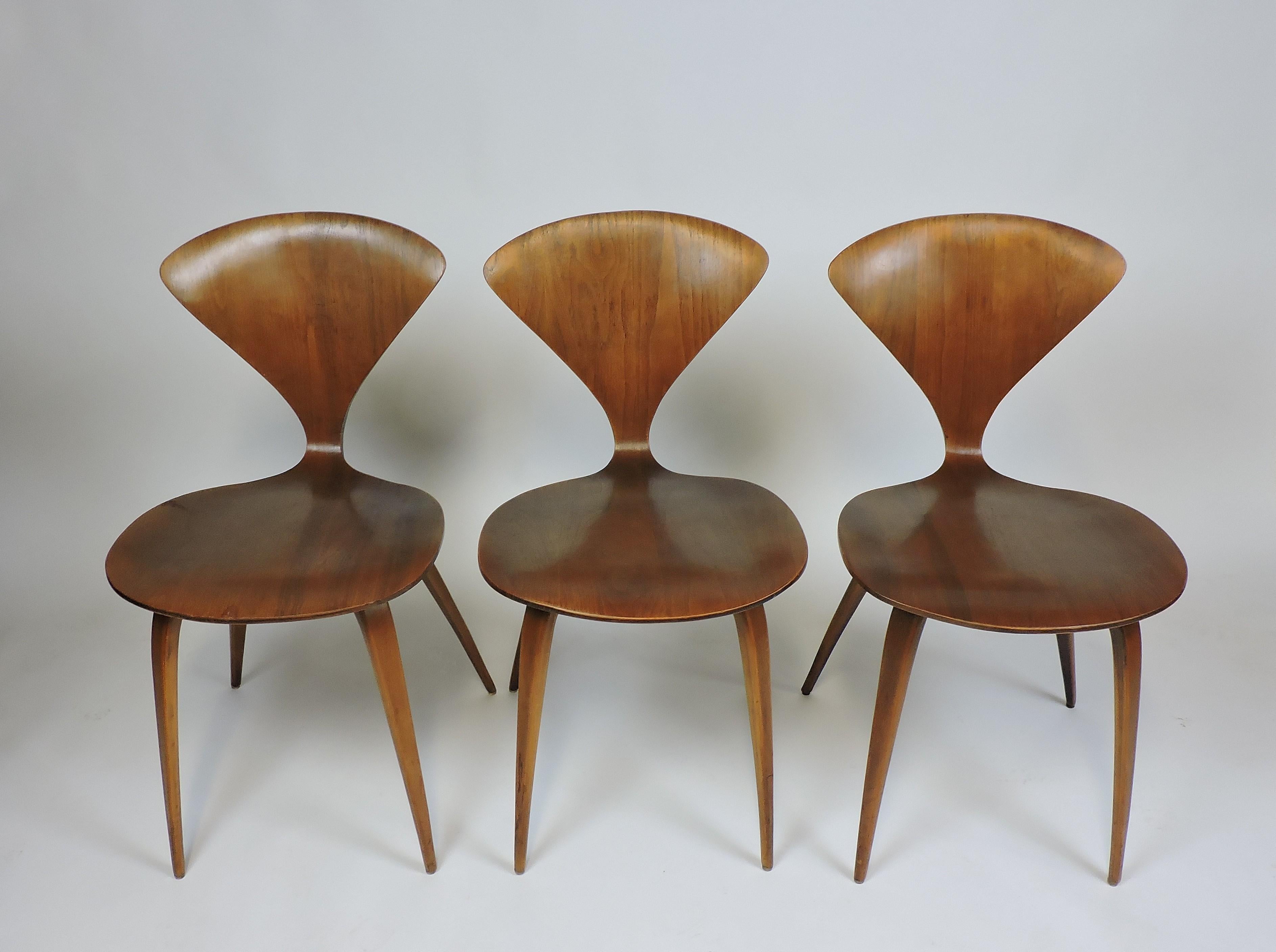Original 1960s set of three dining or side chairs designed by Norman Cherner and manufactured by Plycraft. These bentwood chairs have a Classic midcentury design with beautiful walnut wood grain. Partial Plycraft label to the bottom of one chair.