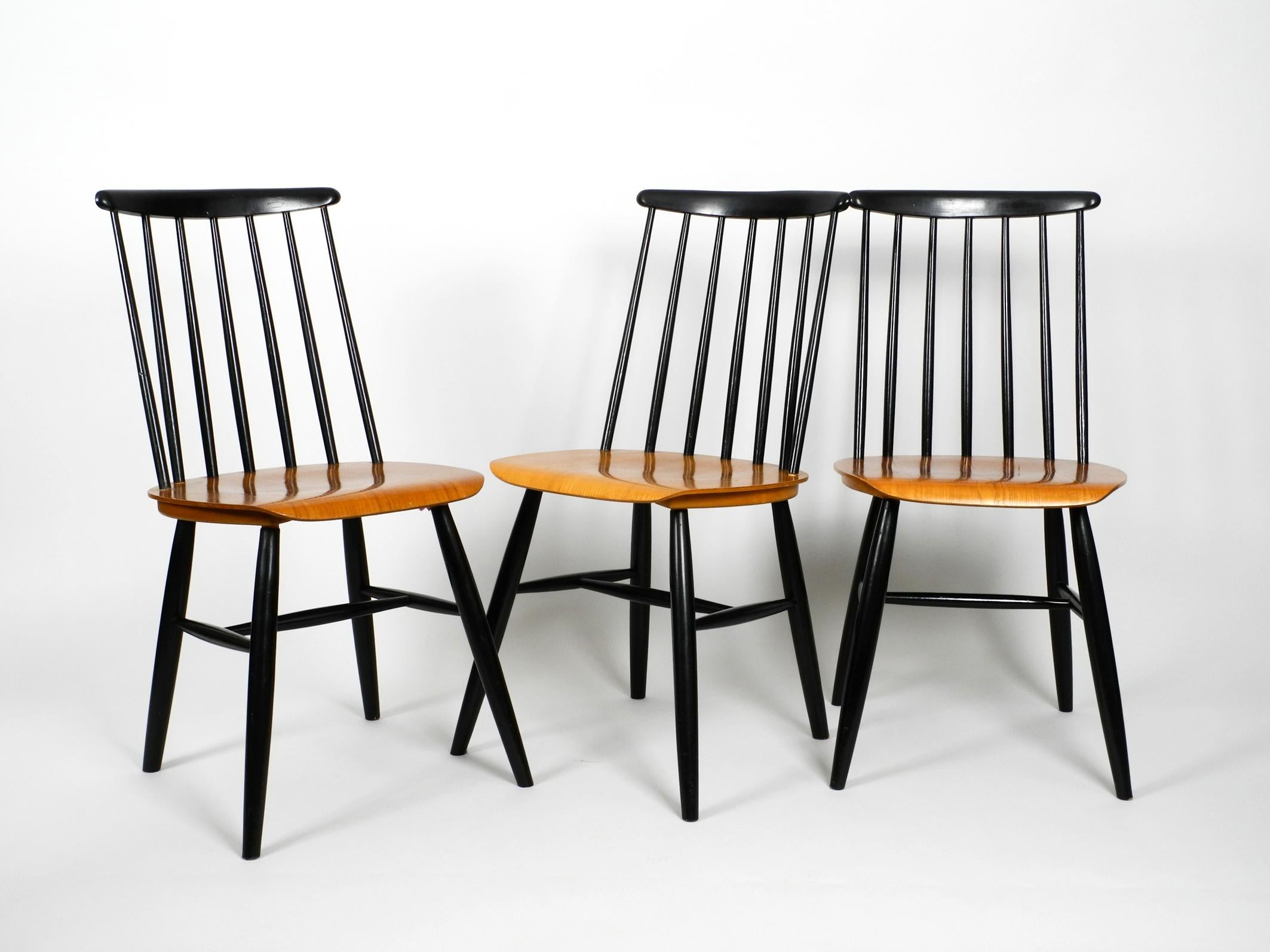 Set of three original midcentury wood spindle back chairs with teak seats. Plywood with teak veneer on top, with black lacquered legs and backrest. 
In the style of Ilmari Tapiovaara.
In very good vintage condition with very few signs of wear.