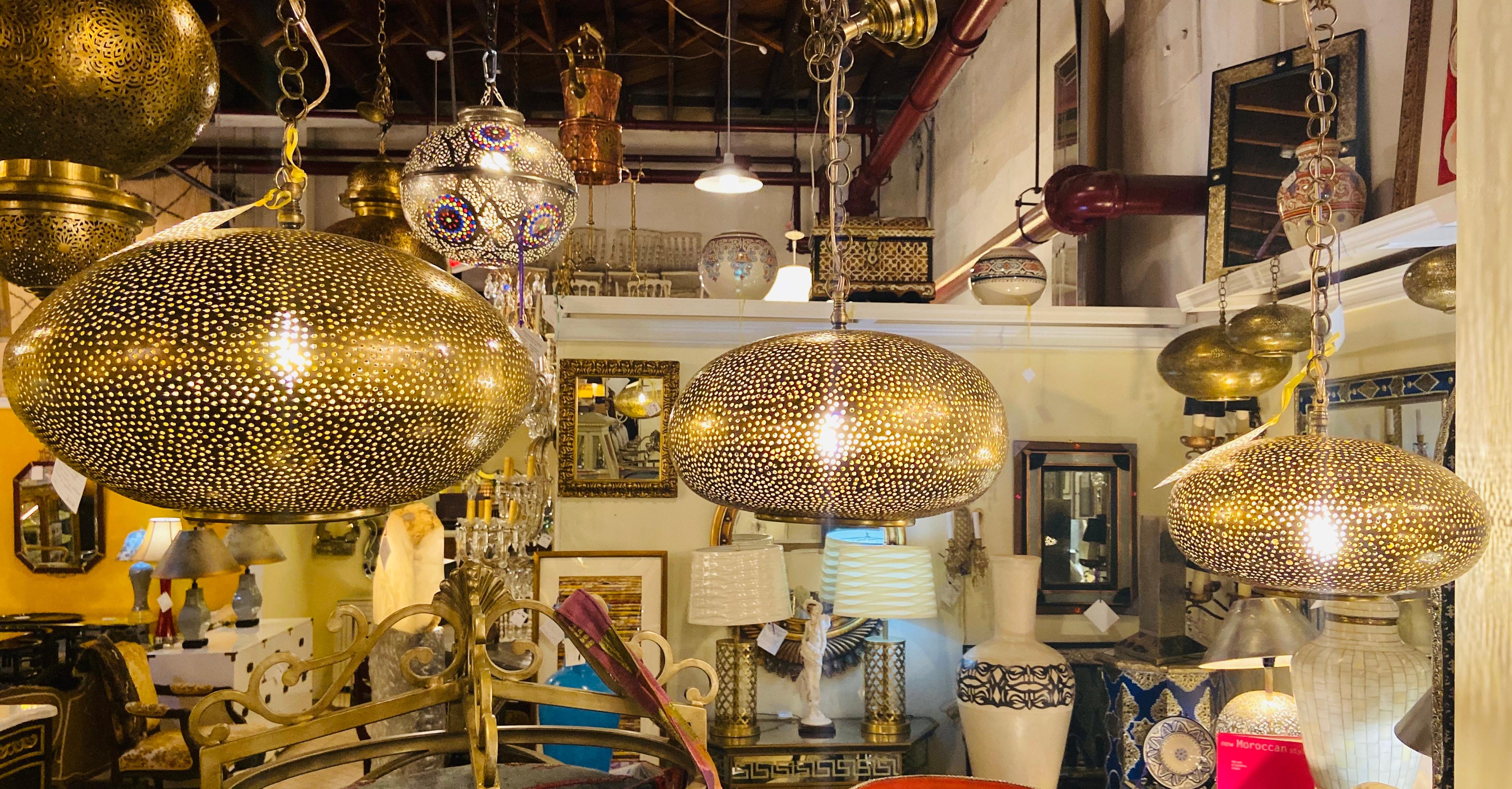 This beautiful set of three artisan-crafted pendant chandeliers will add a note of exotic distinction to any room. Featuring hand-tooled brass and further enhanced with an oval modern shape, these lamps produce a soft ambient lighting perfect for