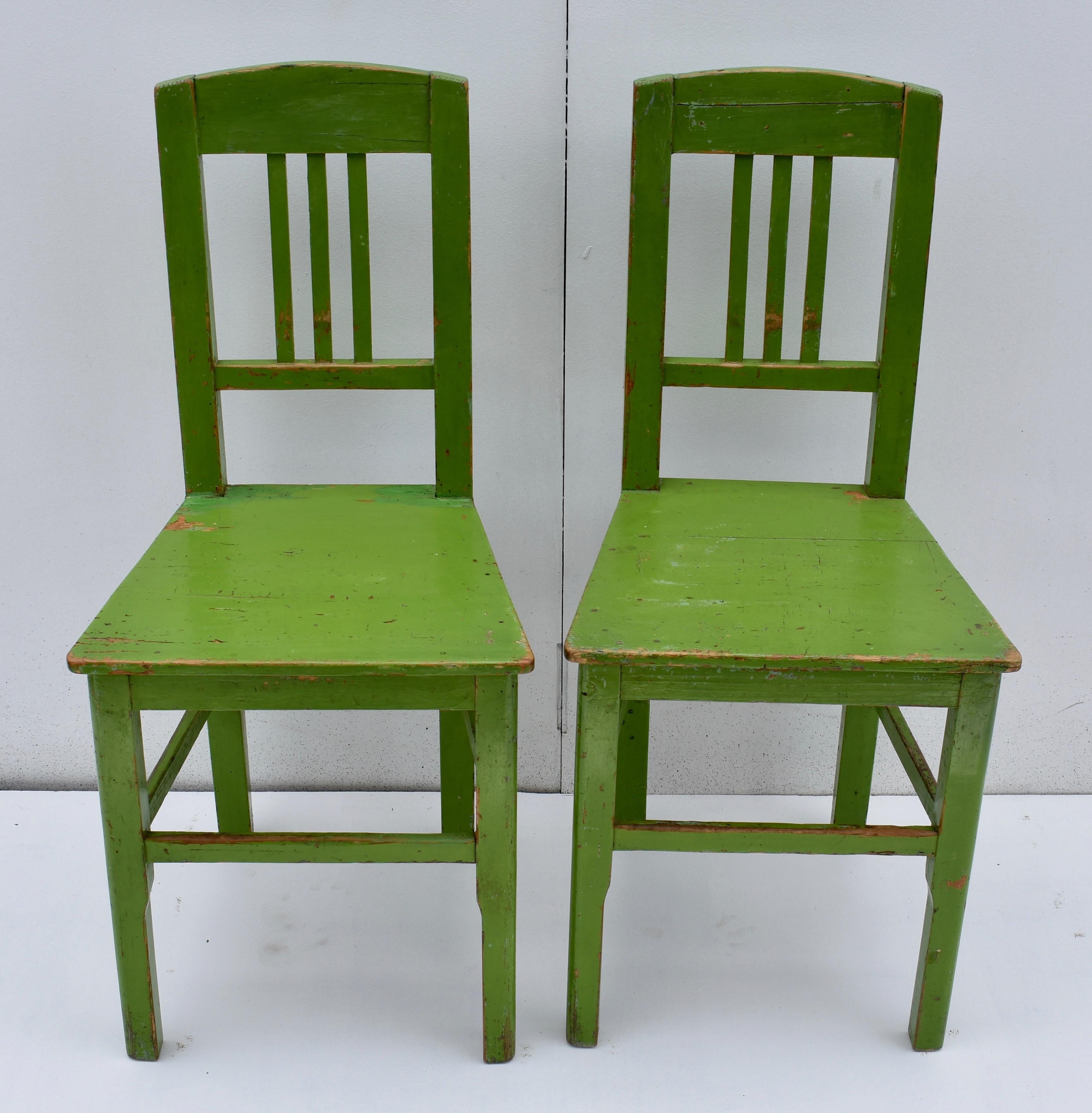 These attractive central European plank-seat Side chairs have three narrow slats to the back and the legs are joined with three mortised-in stretchers. The lower parts of the front legs are nicely chamfered. The worn and chipped green paint has been