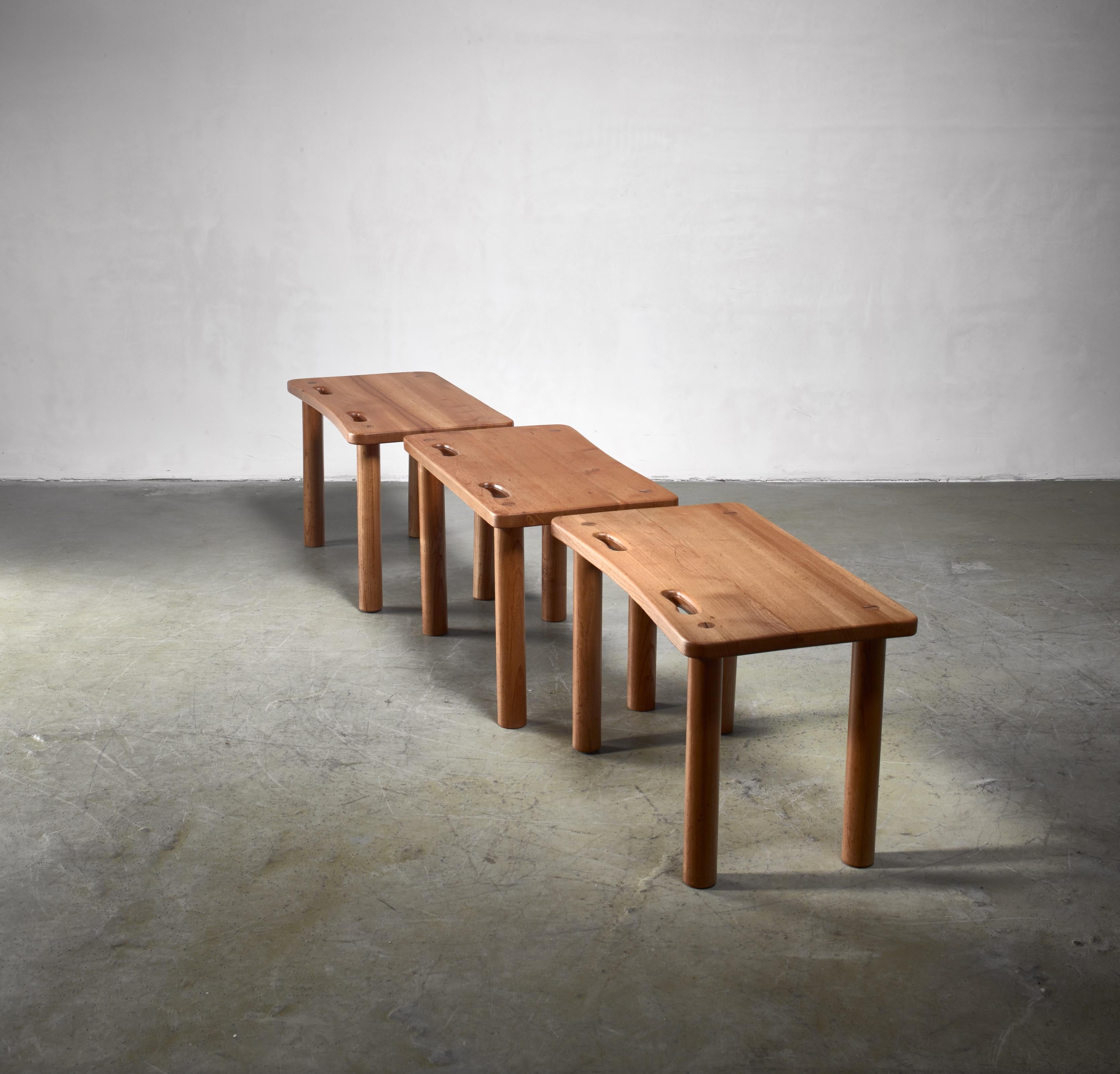 A set of three pine benches or side tables in the Campaign style known from works my Charlotte Perriand, Pierre Chapo and Roland Wilhelmsson. 
They stand on thick round legs and have two grips in the seat.