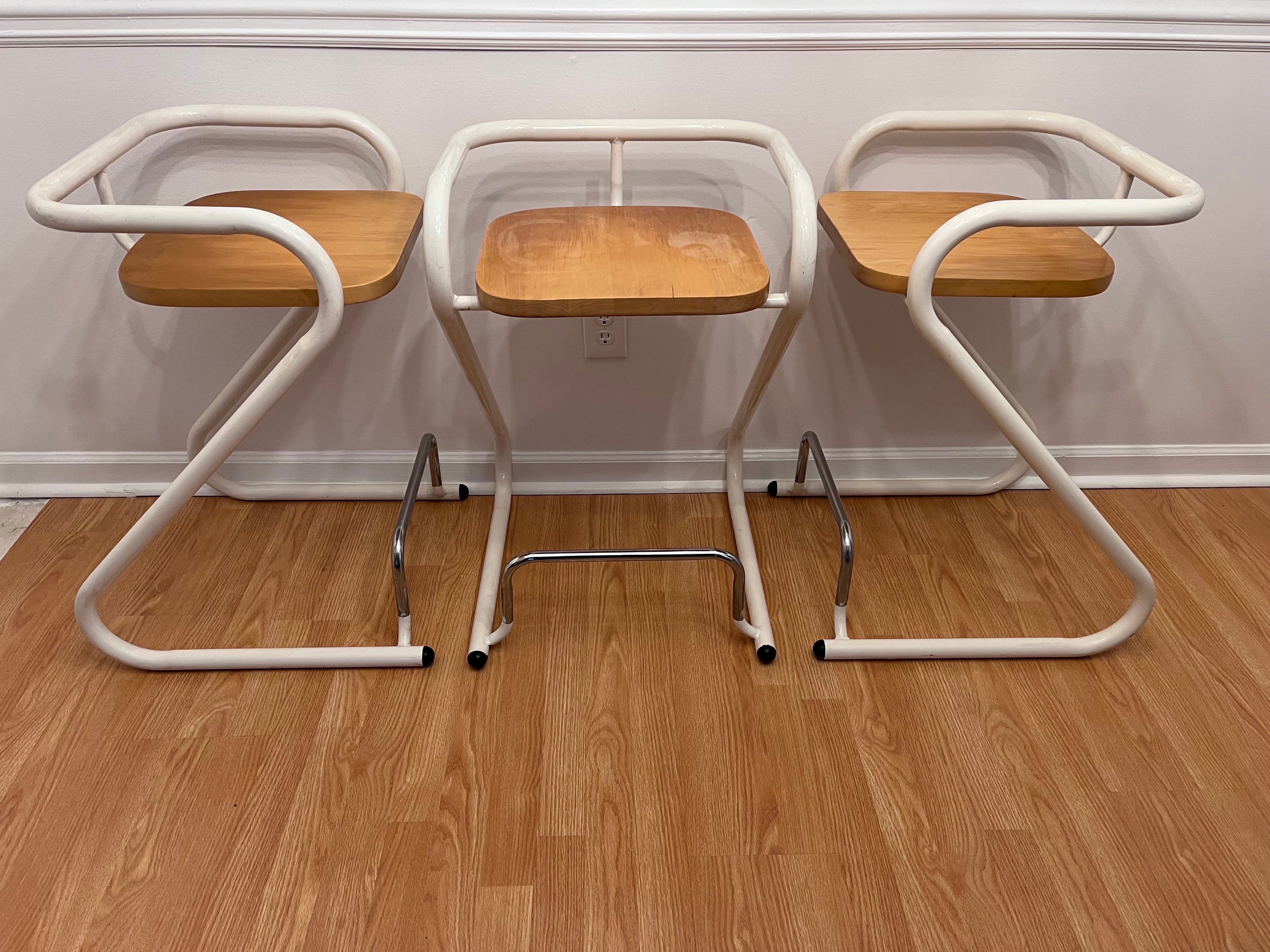 A set of three Z form post modern style circa 1970's tubular steel and wood counter height stools by French Canadien company Les Industries Amisco. The company is also well known for their paper clip form stool. Amisco has been designing beautiful