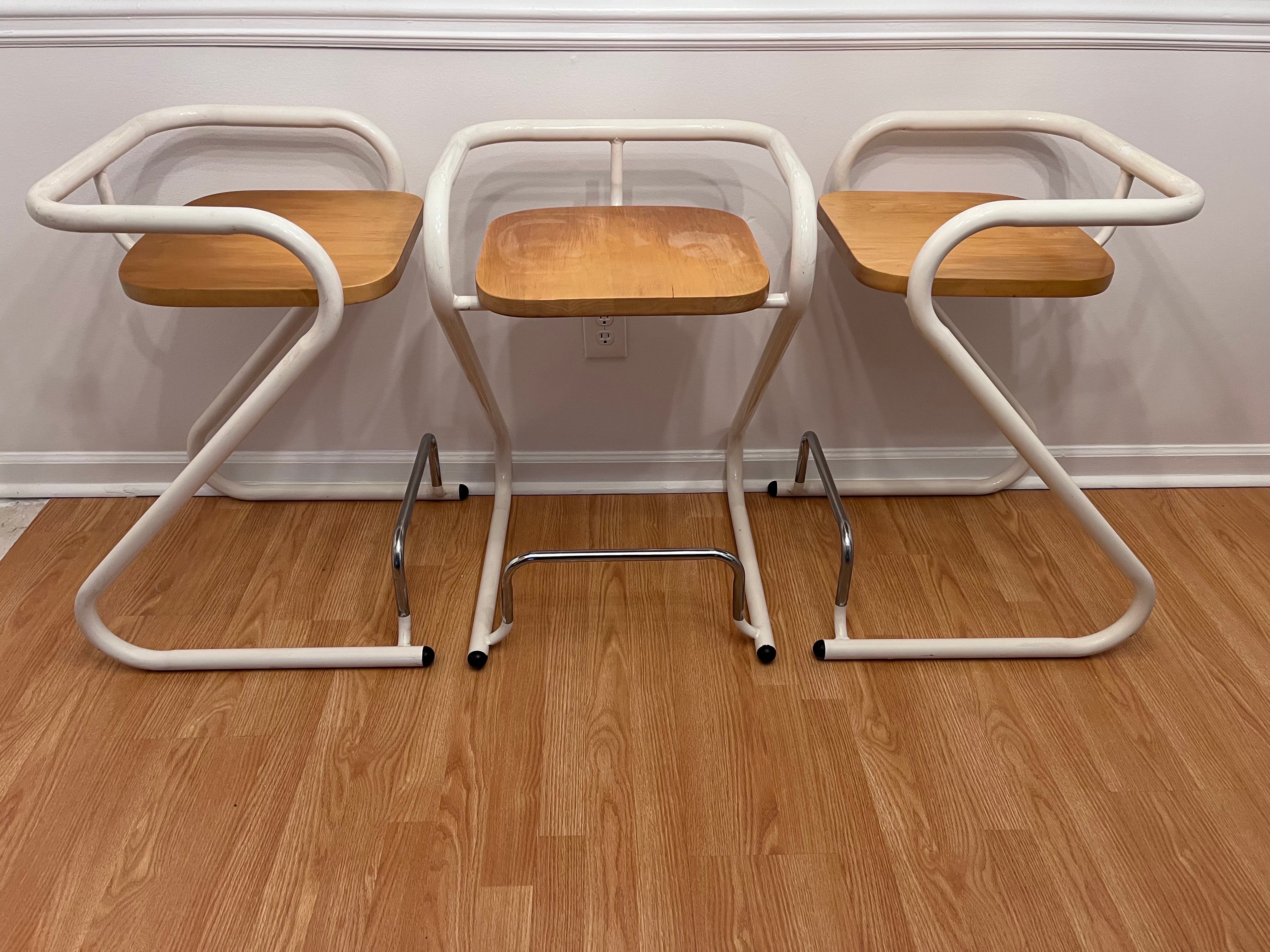 A set of three Z form post modern style circa 1970's tubular steel and wood counter height stools by French Canadien company Les Industries Amisco. The company is also well known for their paper clip form stool. Amisco has been designing beautiful