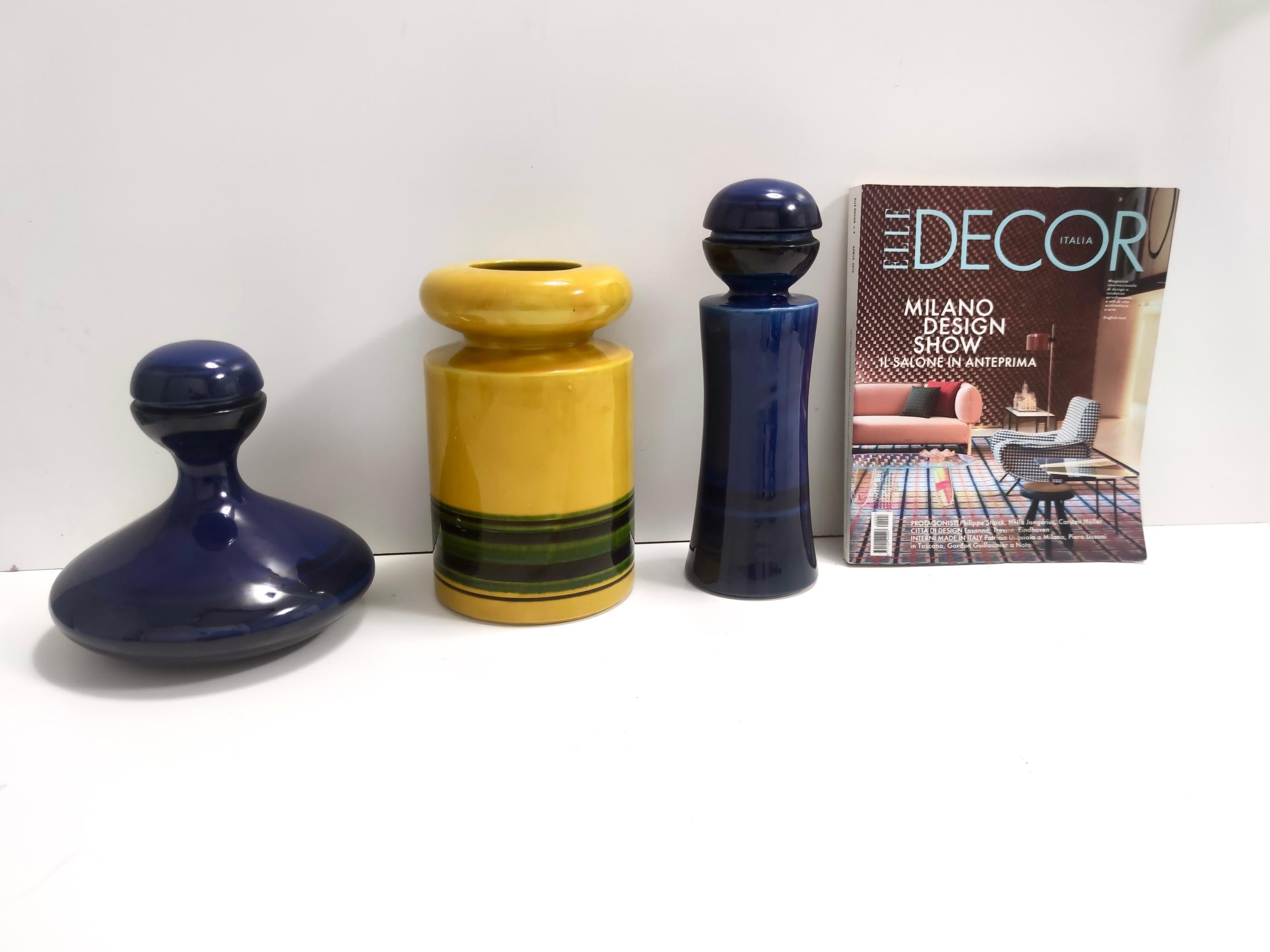 Made in Italy, 1970s.
These two blue bottles and yellow vase are made in glazed ceramic by Parravicini.
Parravicini is not very known as a company, therefore it's not easy to find info about them, but they produce high-quality pieces. 
This is a